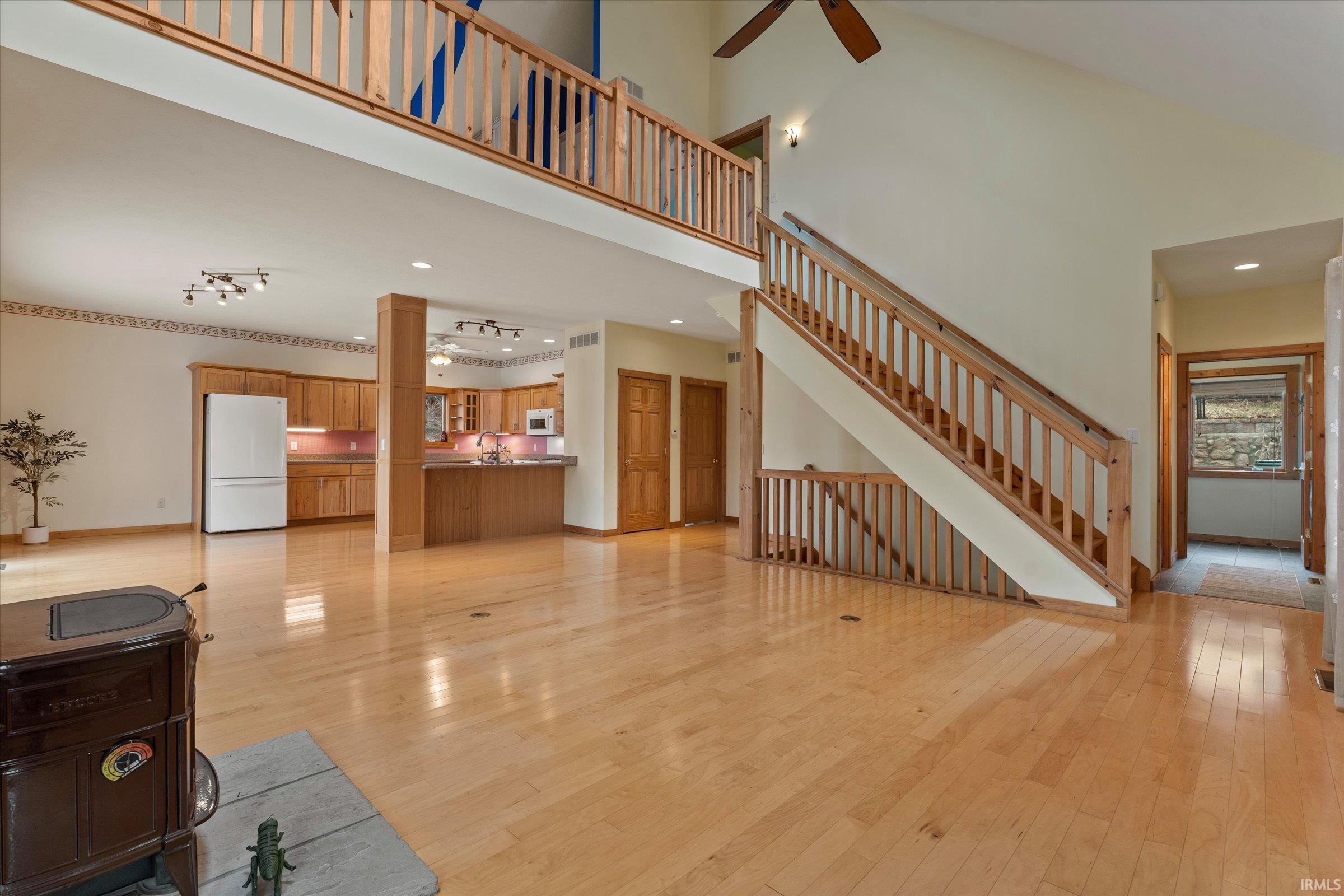 Unfurnished living room featuring light wood finished floors, a high ceiling, a ceiling fan, and recessed lighting