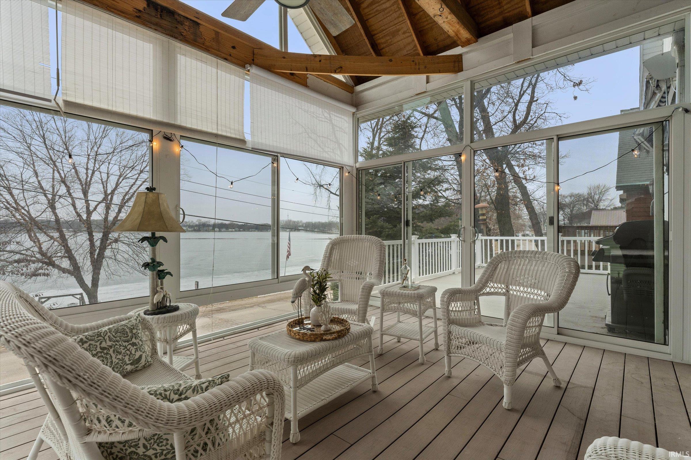 Sunroom / solarium featuring a water view, wood-type flooring, and a high wooden beamed ceiling