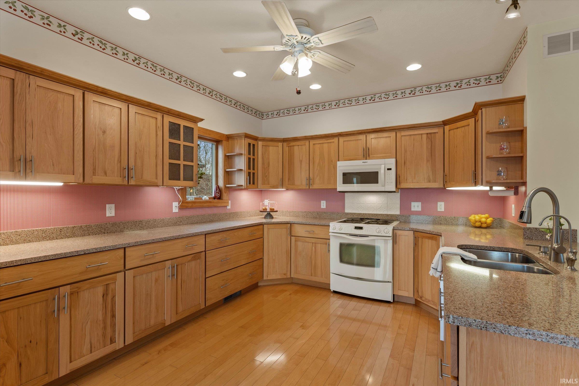 Kitchen featuring open shelves, white appliances, ceiling fan, light stone countertops, and glass fronted cabinets