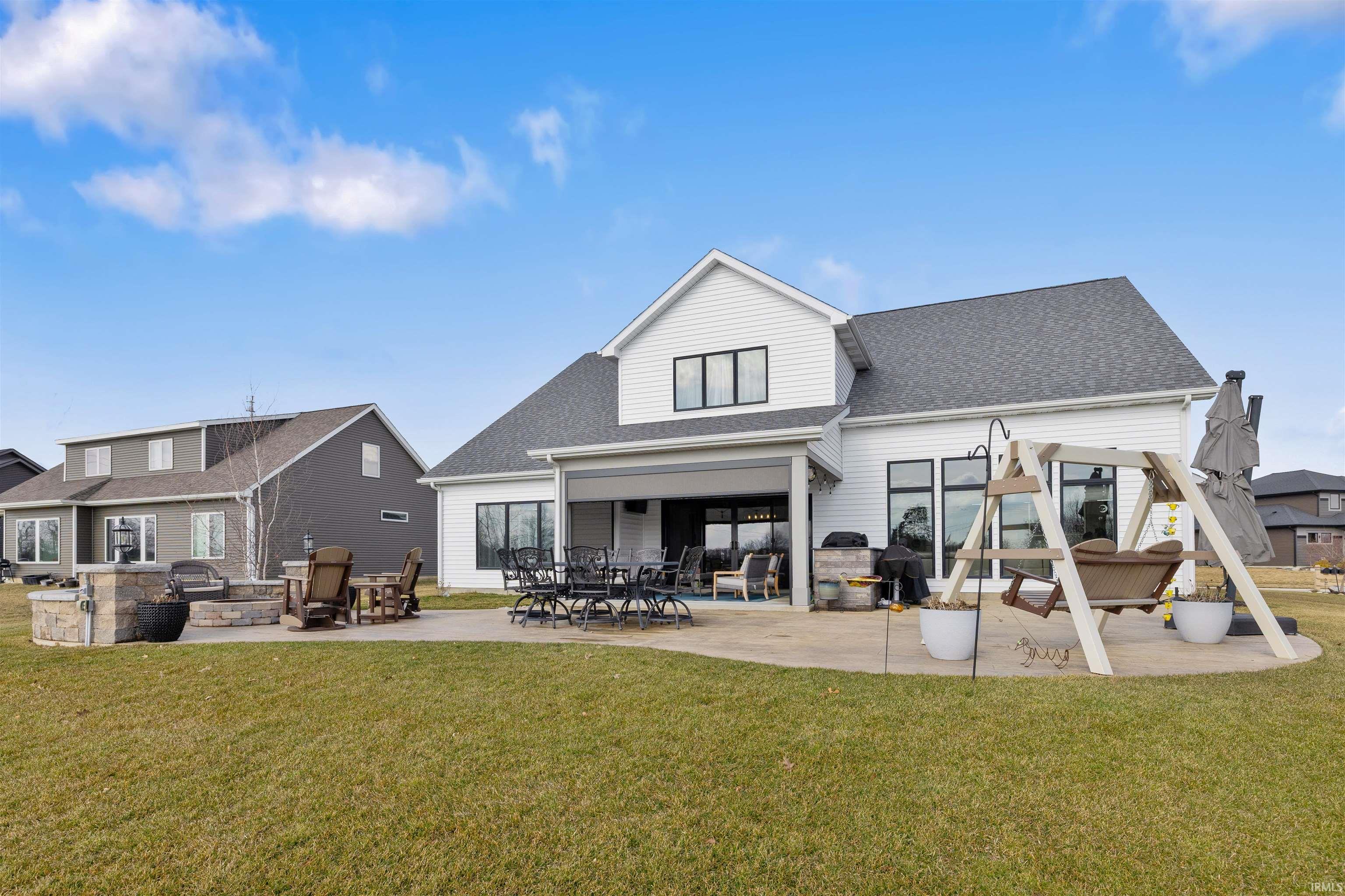 Back of property with a patio area, a lawn, and a shingled roof