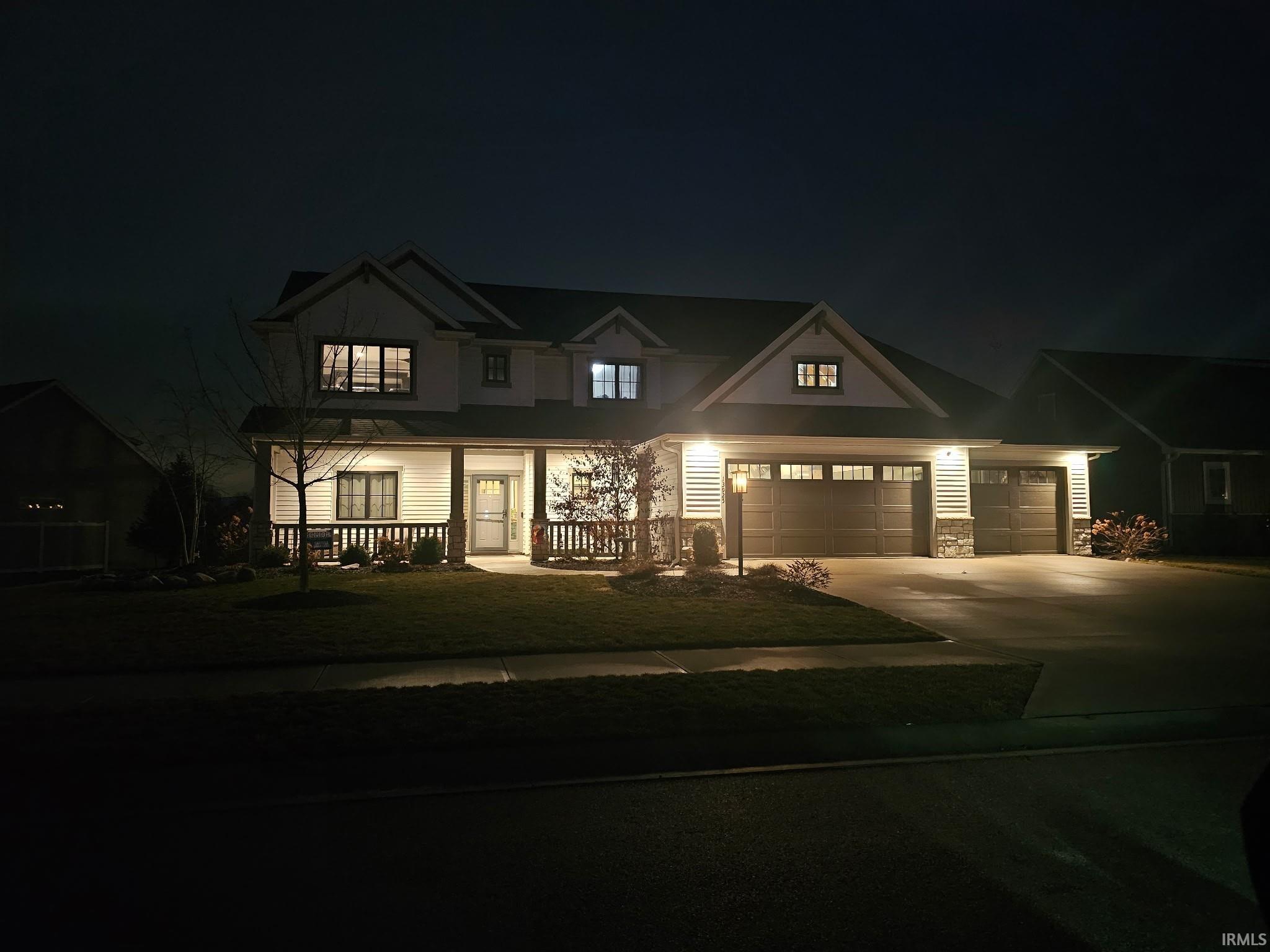Craftsman-style home featuring driveway, stone siding, a porch, a lawn, and a garage