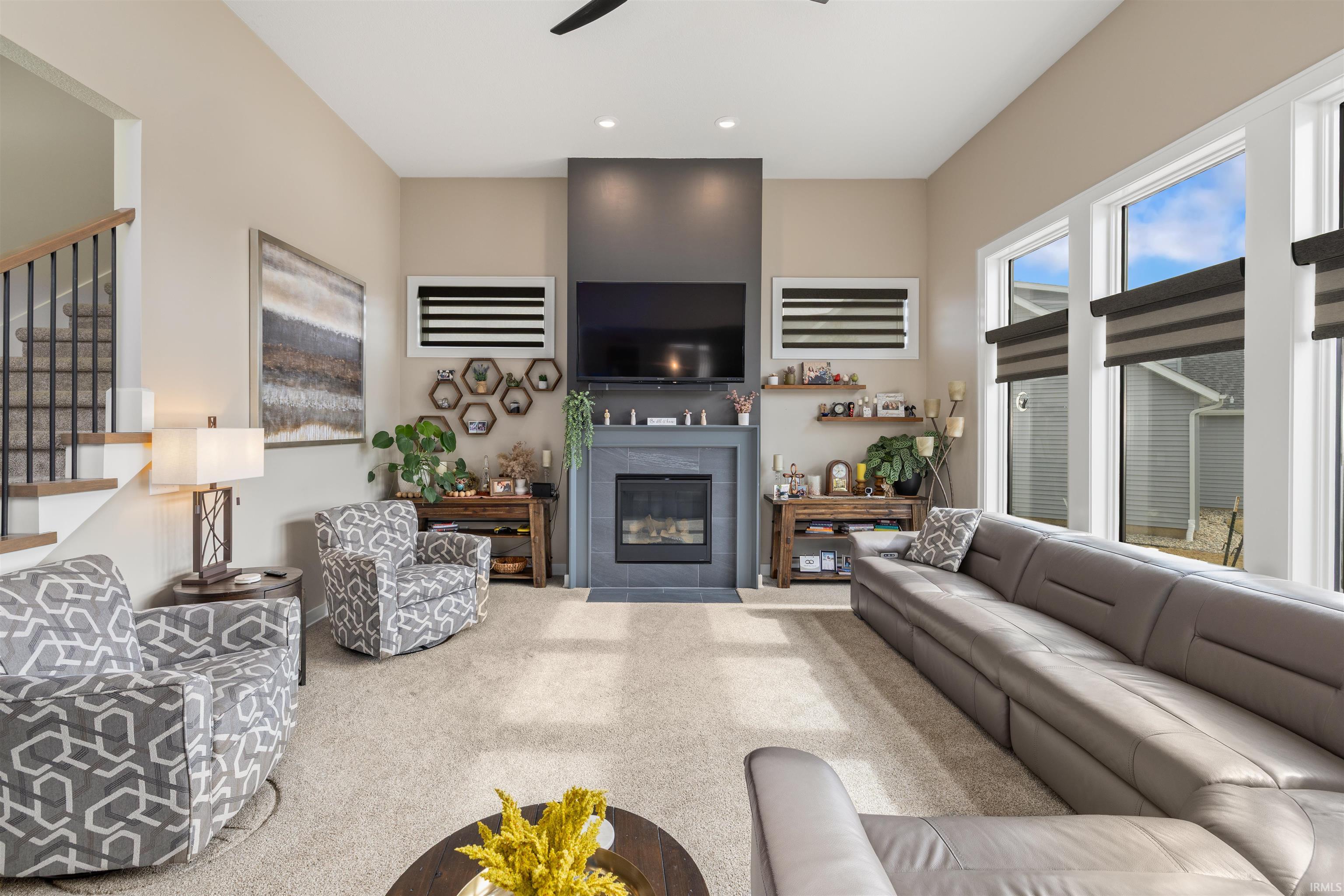 Carpeted living room with a fireplace, ceiling fan, and recessed lighting