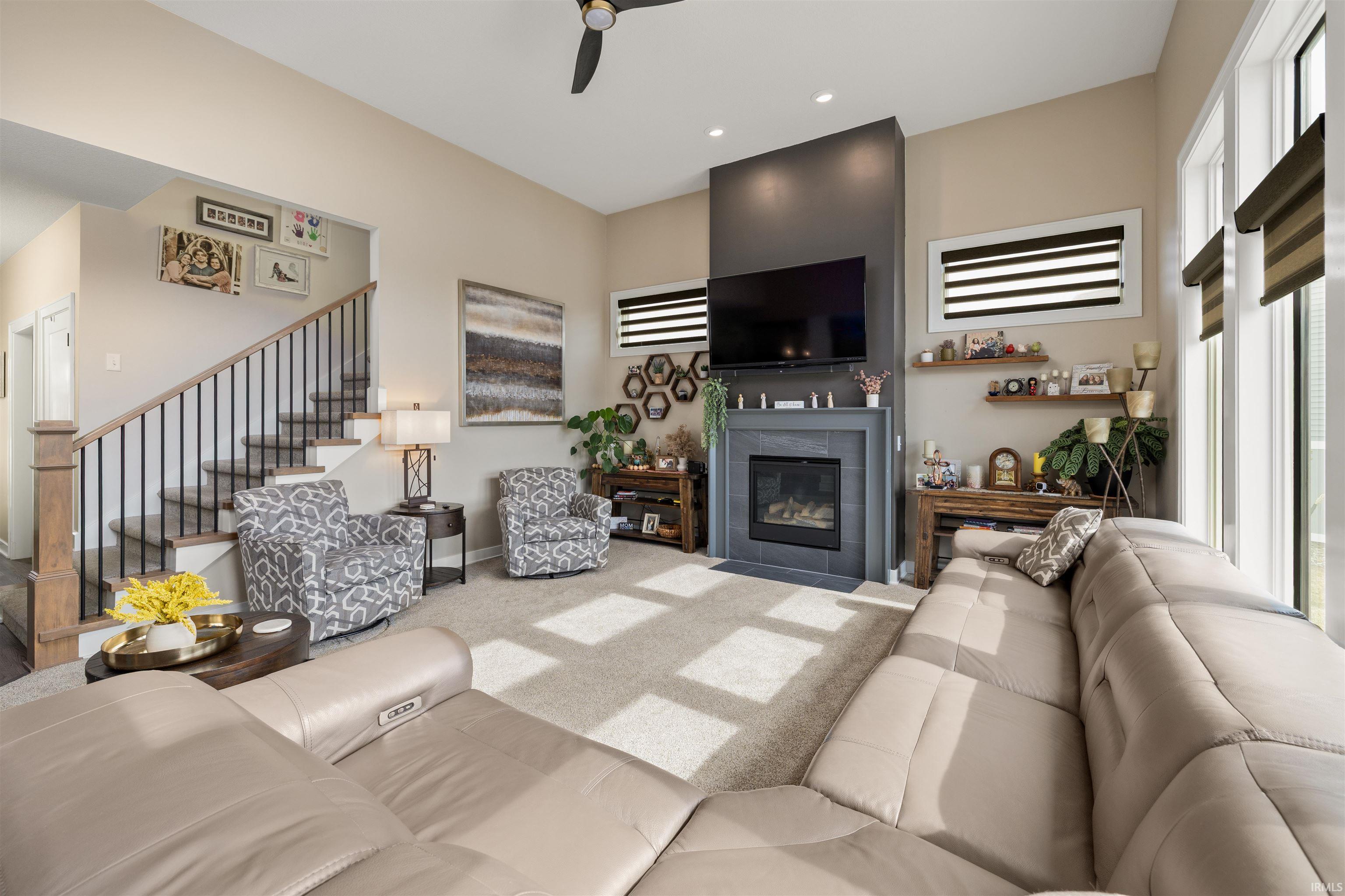 Living room with a tile fireplace, carpet, ceiling fan, and recessed lighting