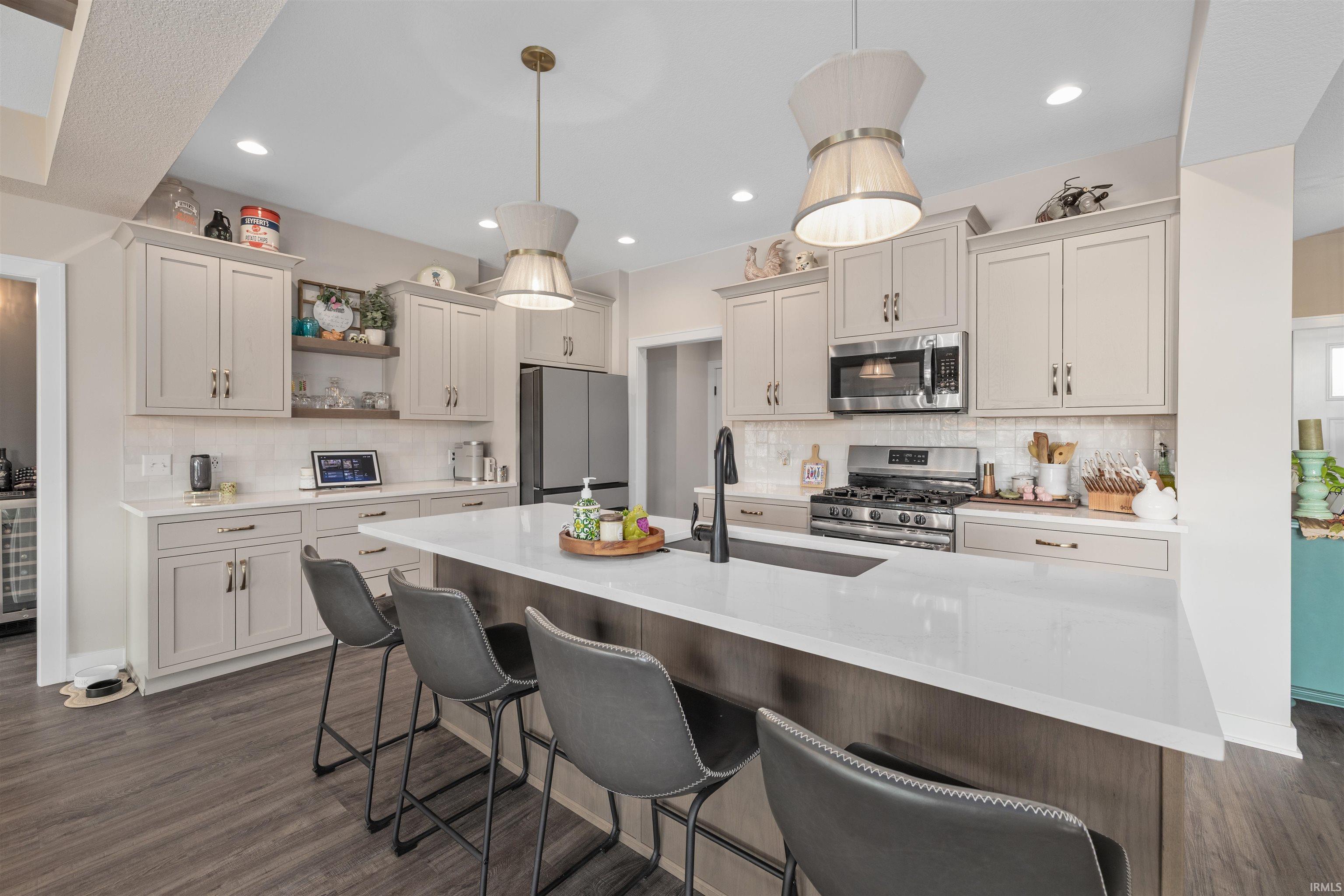 Kitchen featuring a kitchen bar, stainless steel appliances, dark wood-style flooring, open shelves, and light stone counters