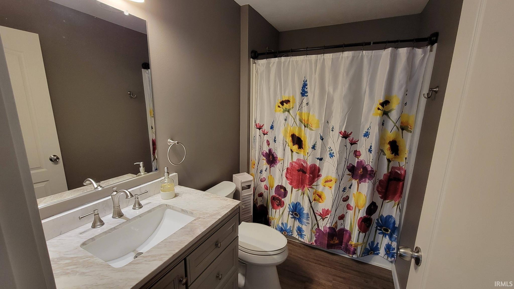 Bathroom with vanity, curtained shower, and dark wood-type flooring