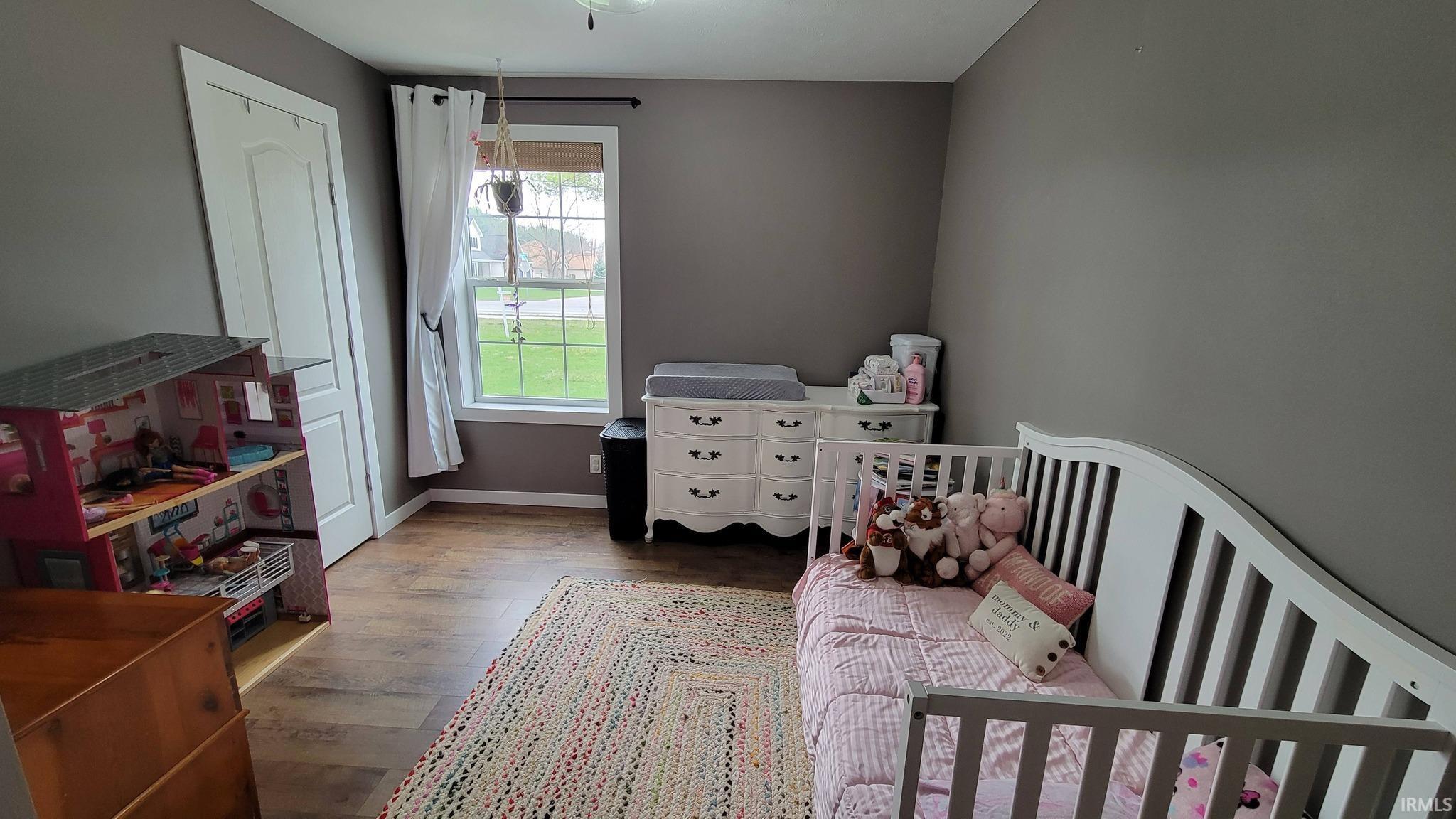 Bedroom with wood finished floors and a nursery area