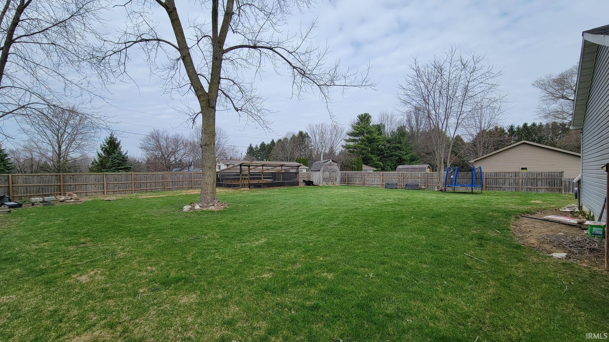 Fenced backyard with a wooden deck and an outdoor structure