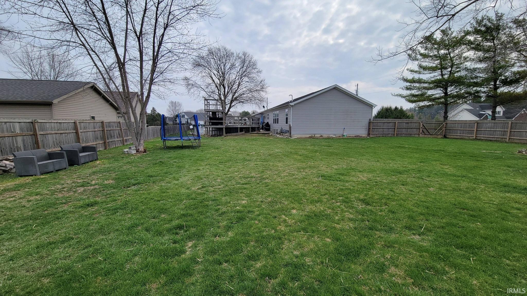 Fenced backyard featuring a trampoline
