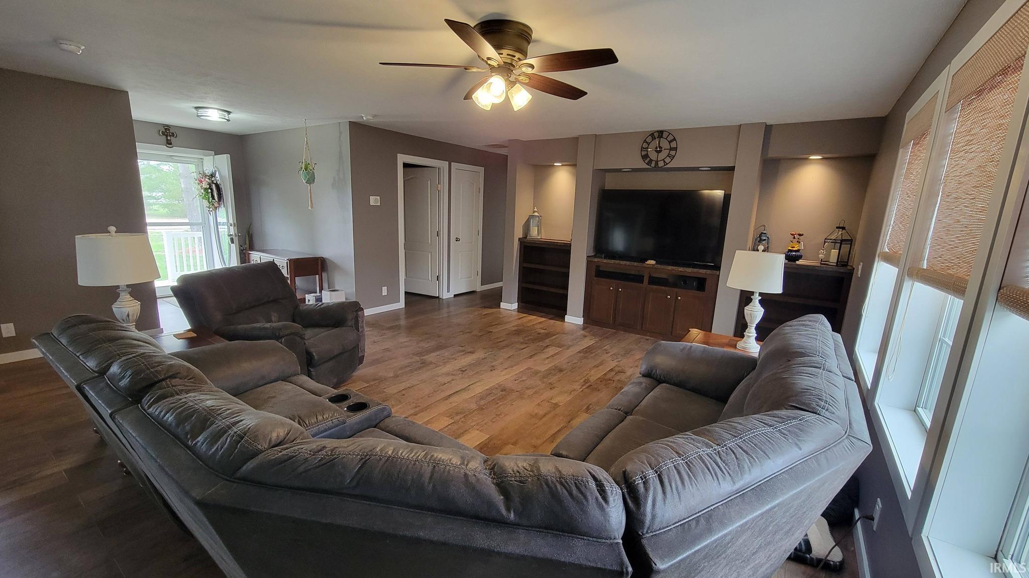 Living area with a ceiling fan and dark wood-style floors