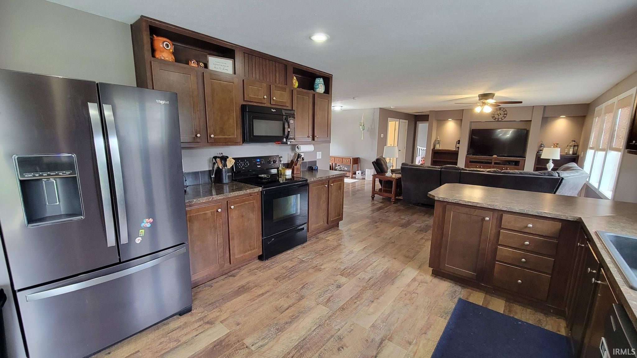 Kitchen with black appliances, open shelves, light wood-style flooring, open floor plan, and a ceiling fan