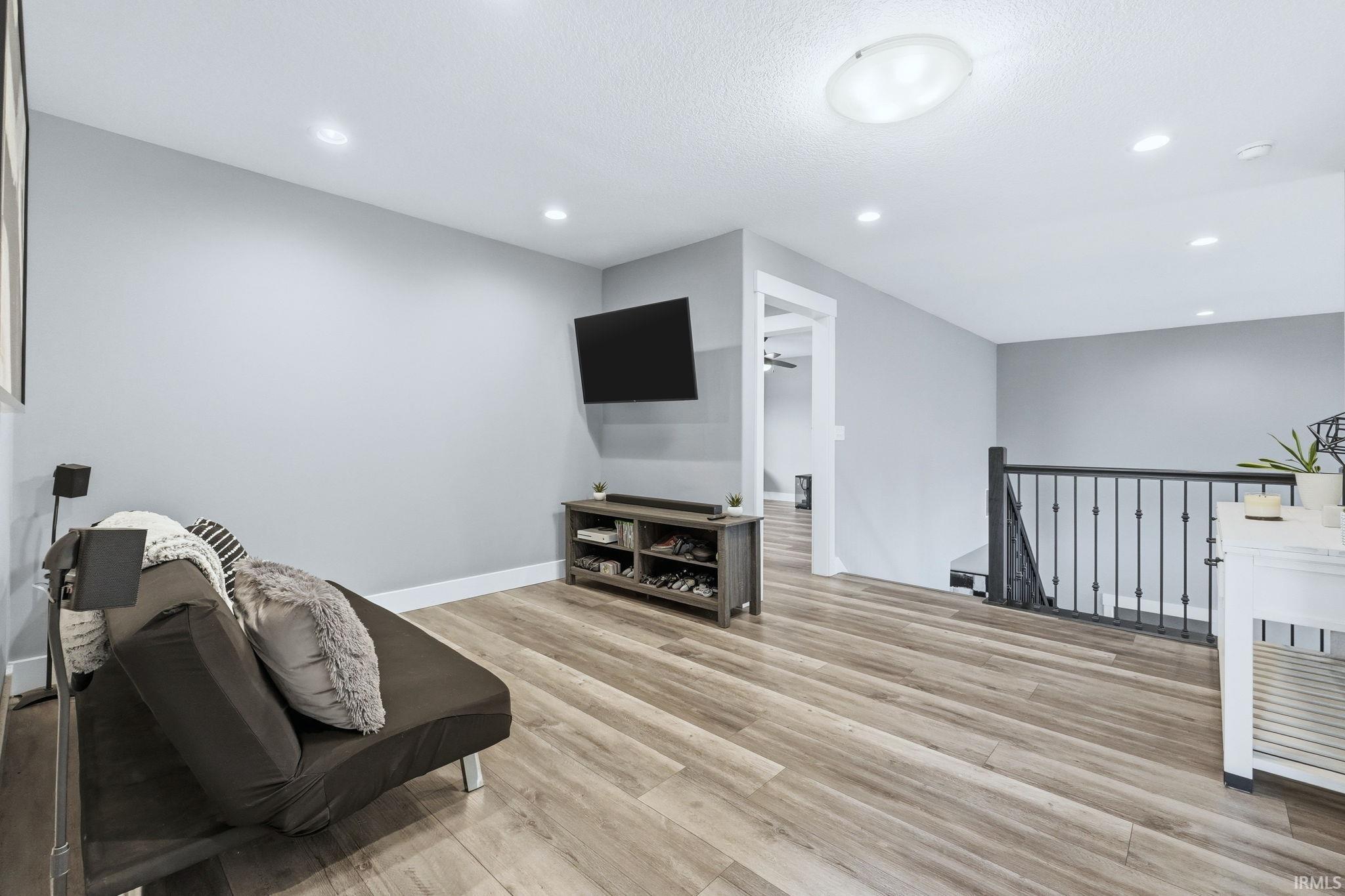 Sitting room featuring an upstairs landing, light wood finished floors, and recessed lighting