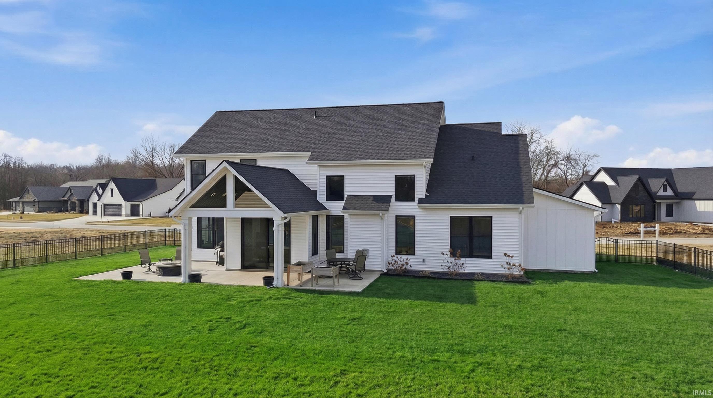 Back of house featuring a shingled roof, a patio, a fenced backyard, and a residential view. Landscaping color enhanced.
