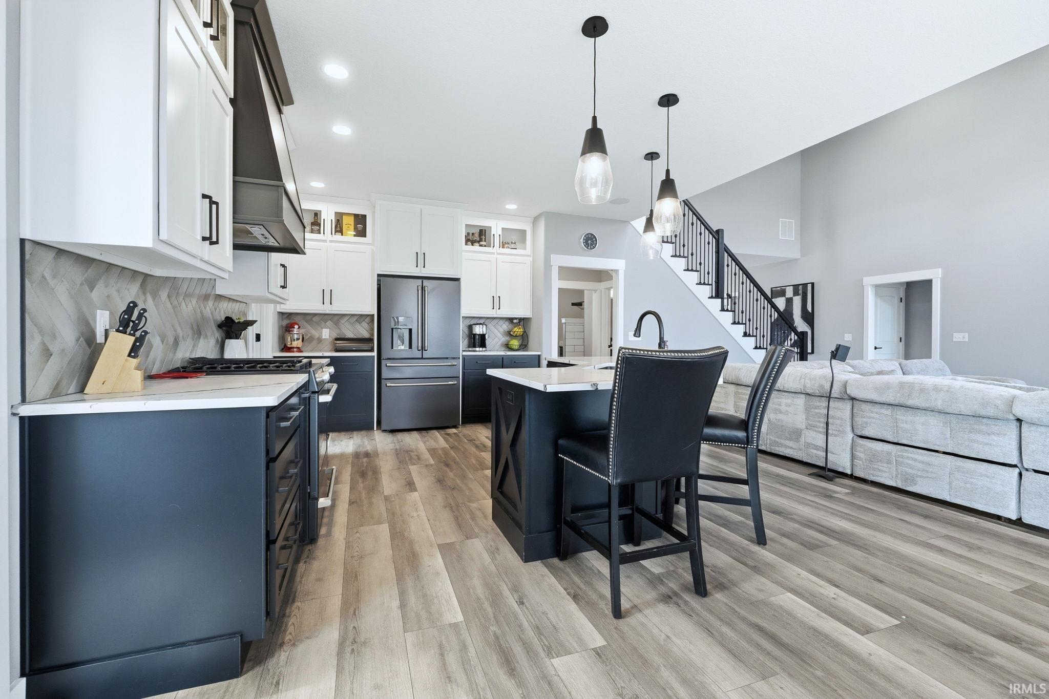 Kitchen with two tone color scheme, a kitchen island with sink, high end fridge, open floor plan, and a breakfast bar