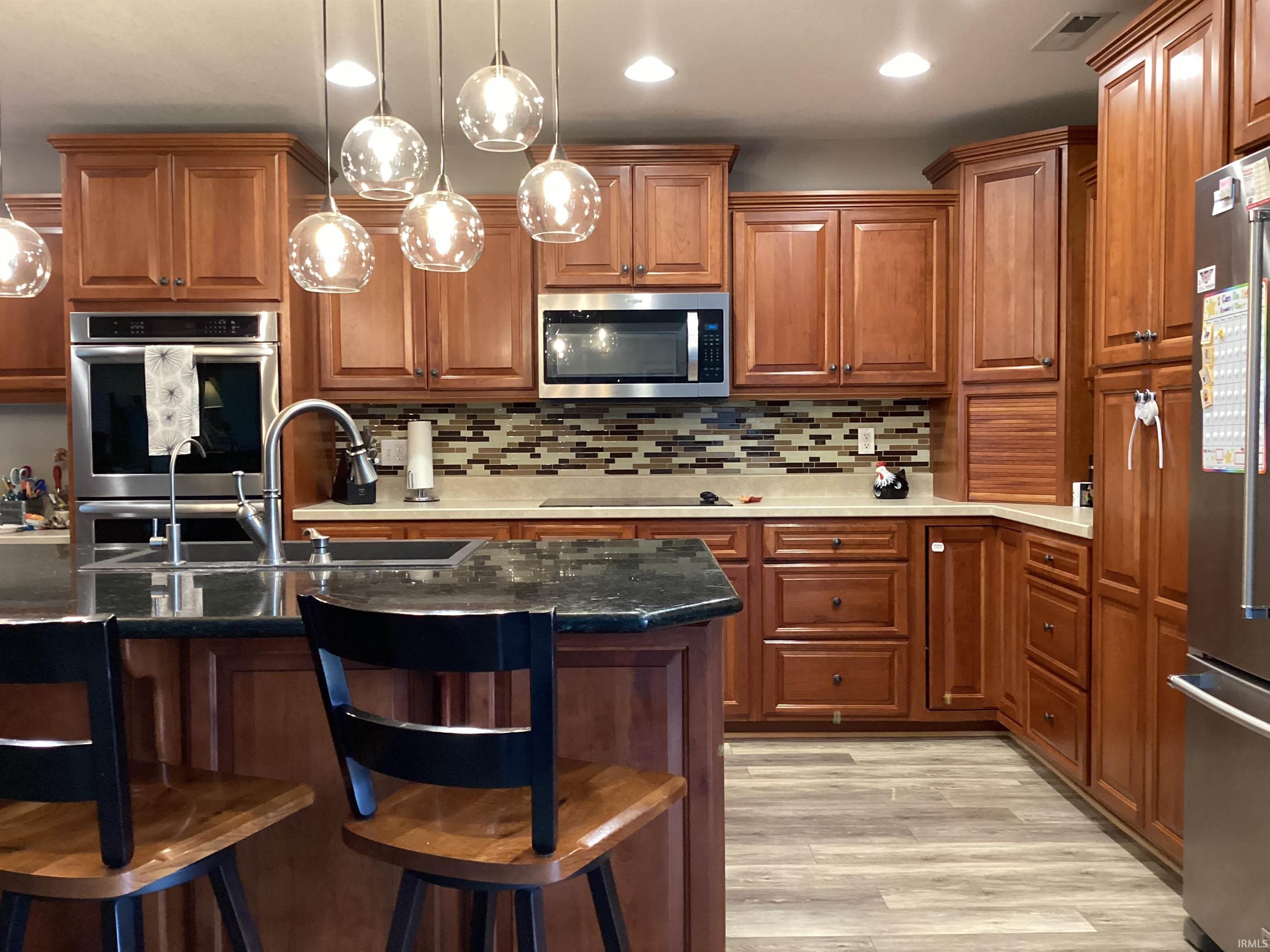 Kitchen with a breakfast bar area, wood finish cabinets, stainless steel appliances, and hanging light fixtures