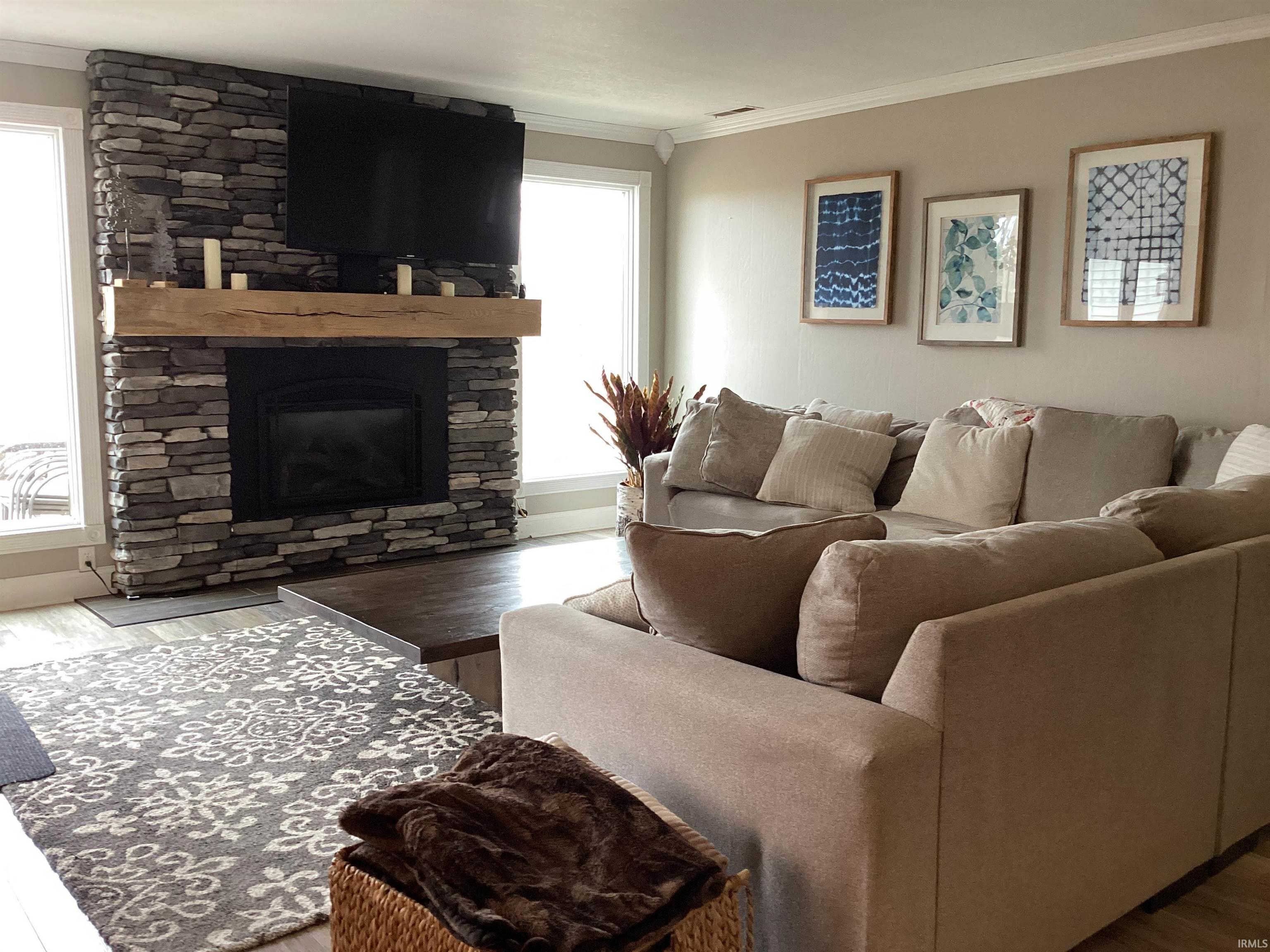 Living room with ornamental molding, wood finished floors, and a fireplace