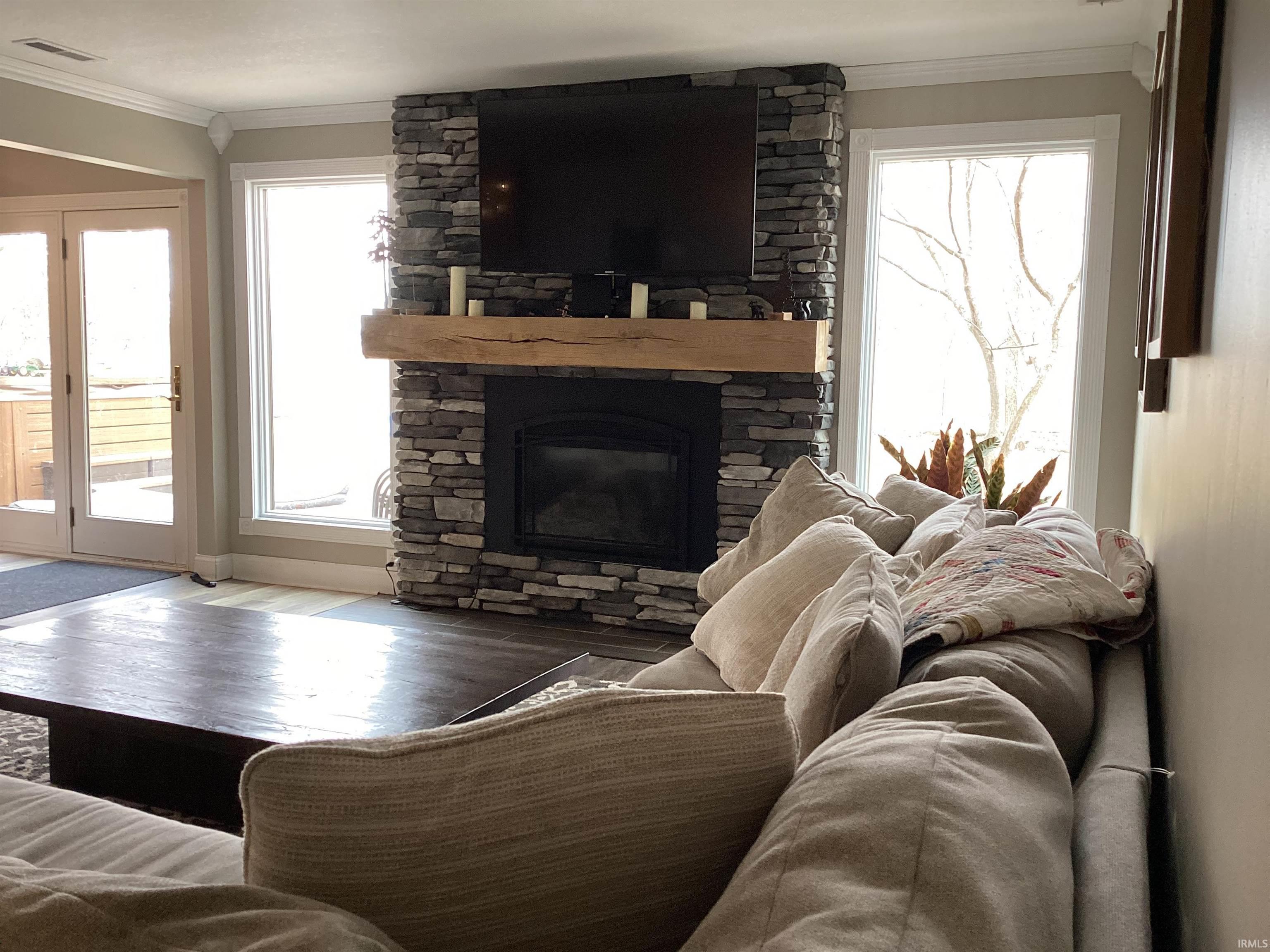 Living area with crown molding, a fireplace, and wood finished floors