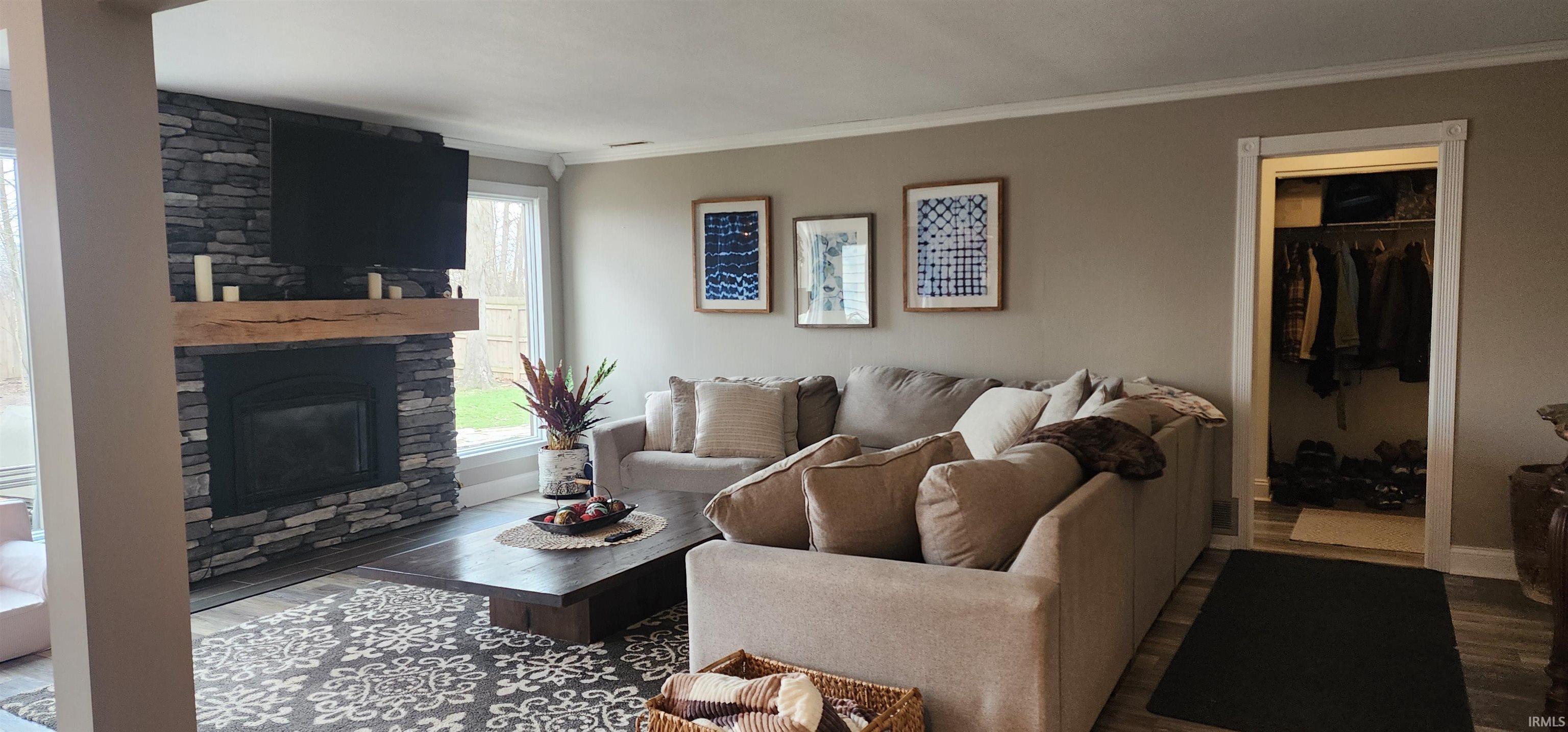 Living room with ornamental molding, a fireplace, and wood finished floors