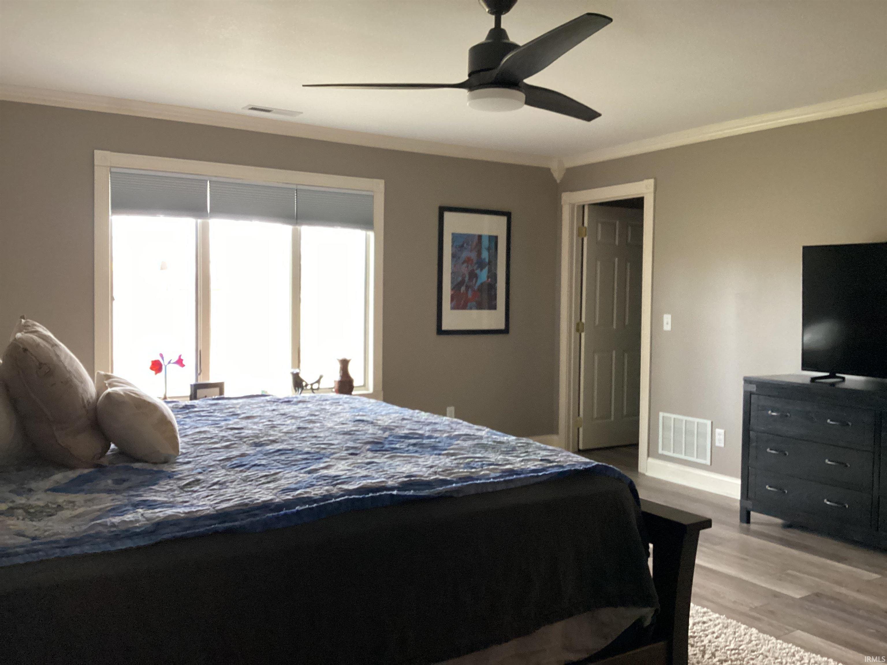 Bedroom with crown molding, light wood finished floors, and ceiling fan
