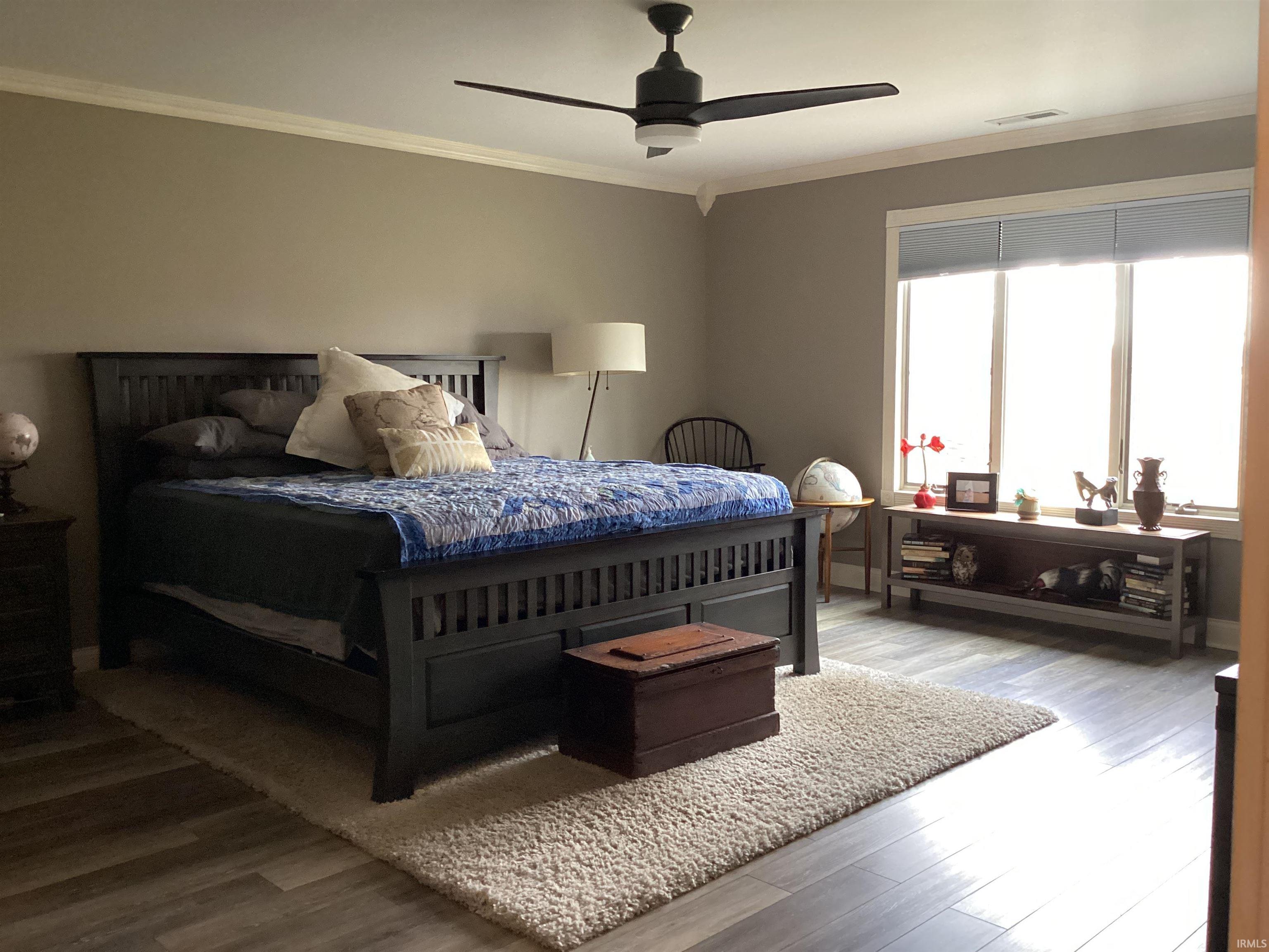 Bedroom with crown molding, wood finished floors, and a ceiling fan