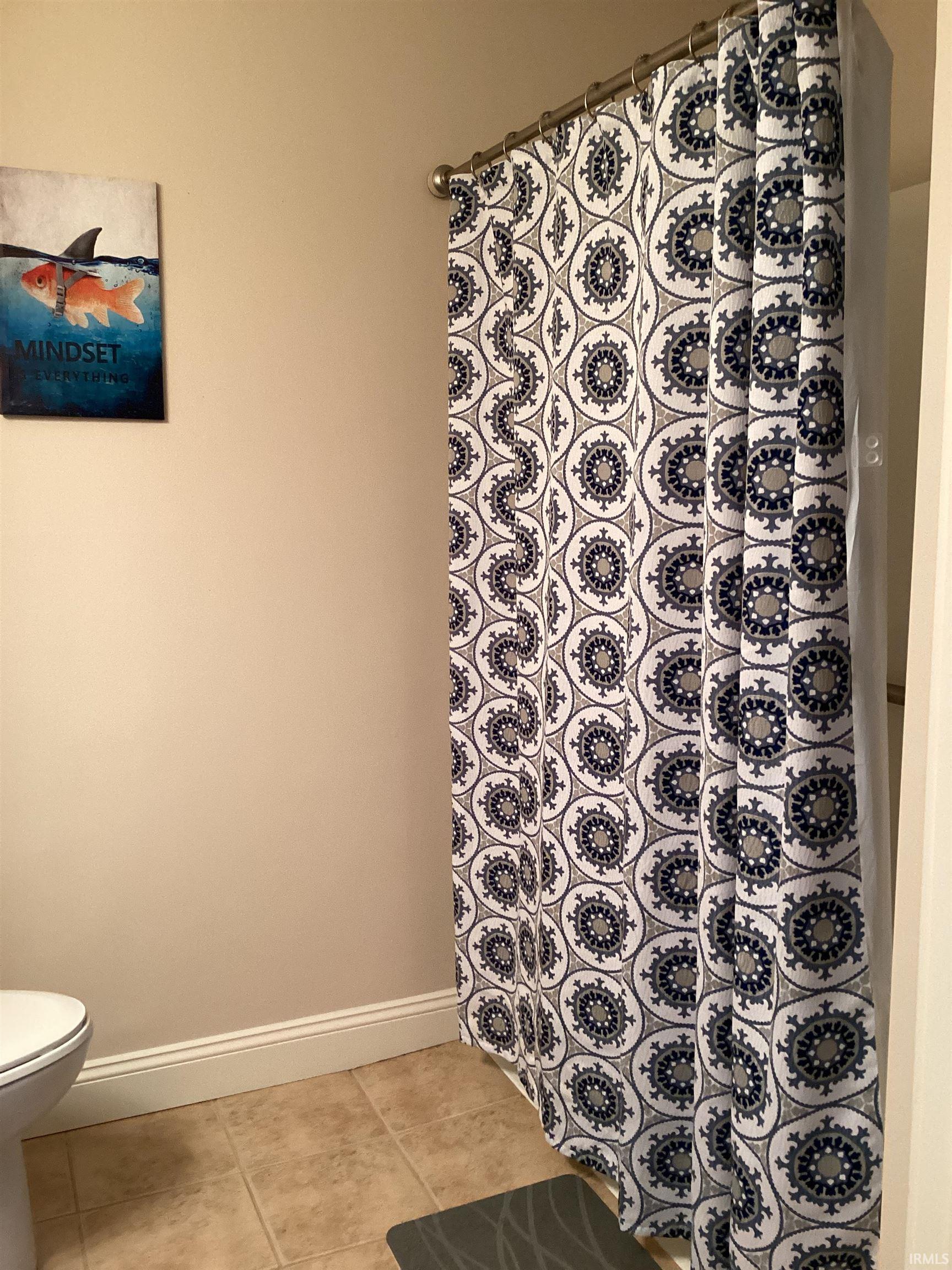 Full bathroom featuring curtained shower and light tile patterned floors