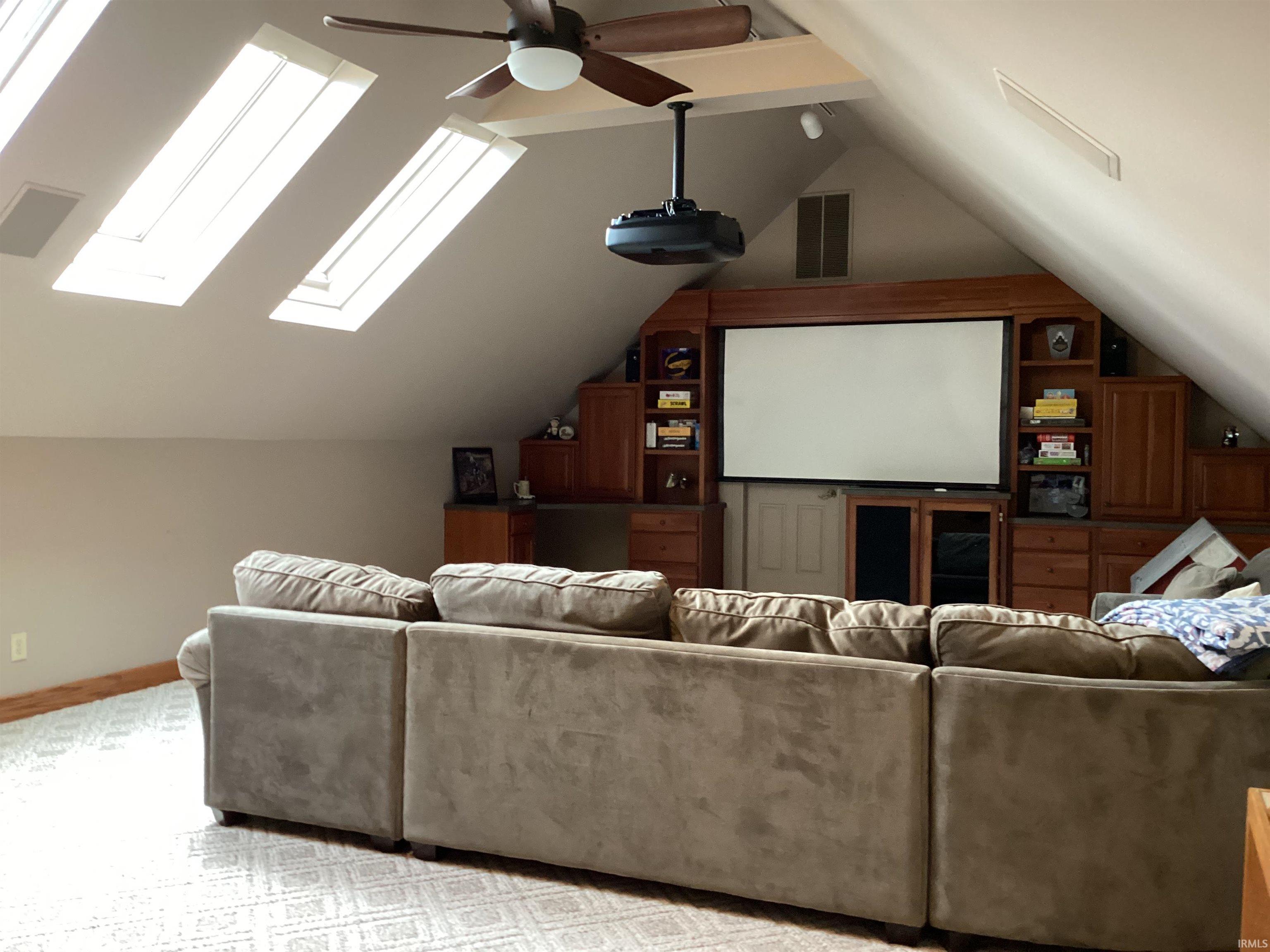 Cinema featuring a ceiling fan, light colored carpet, and a skylight