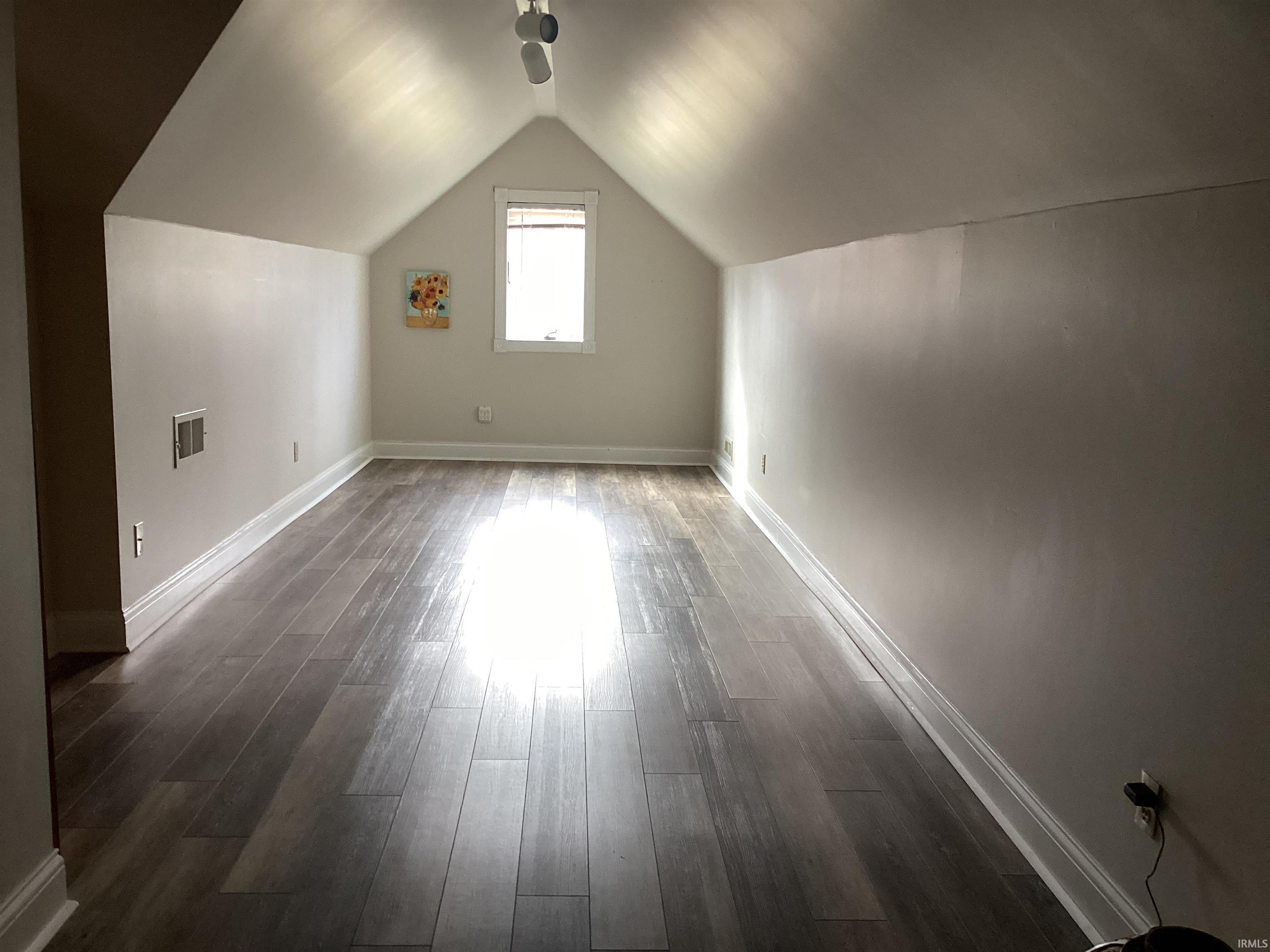 Bonus room with baseboards and dark wood-type flooring