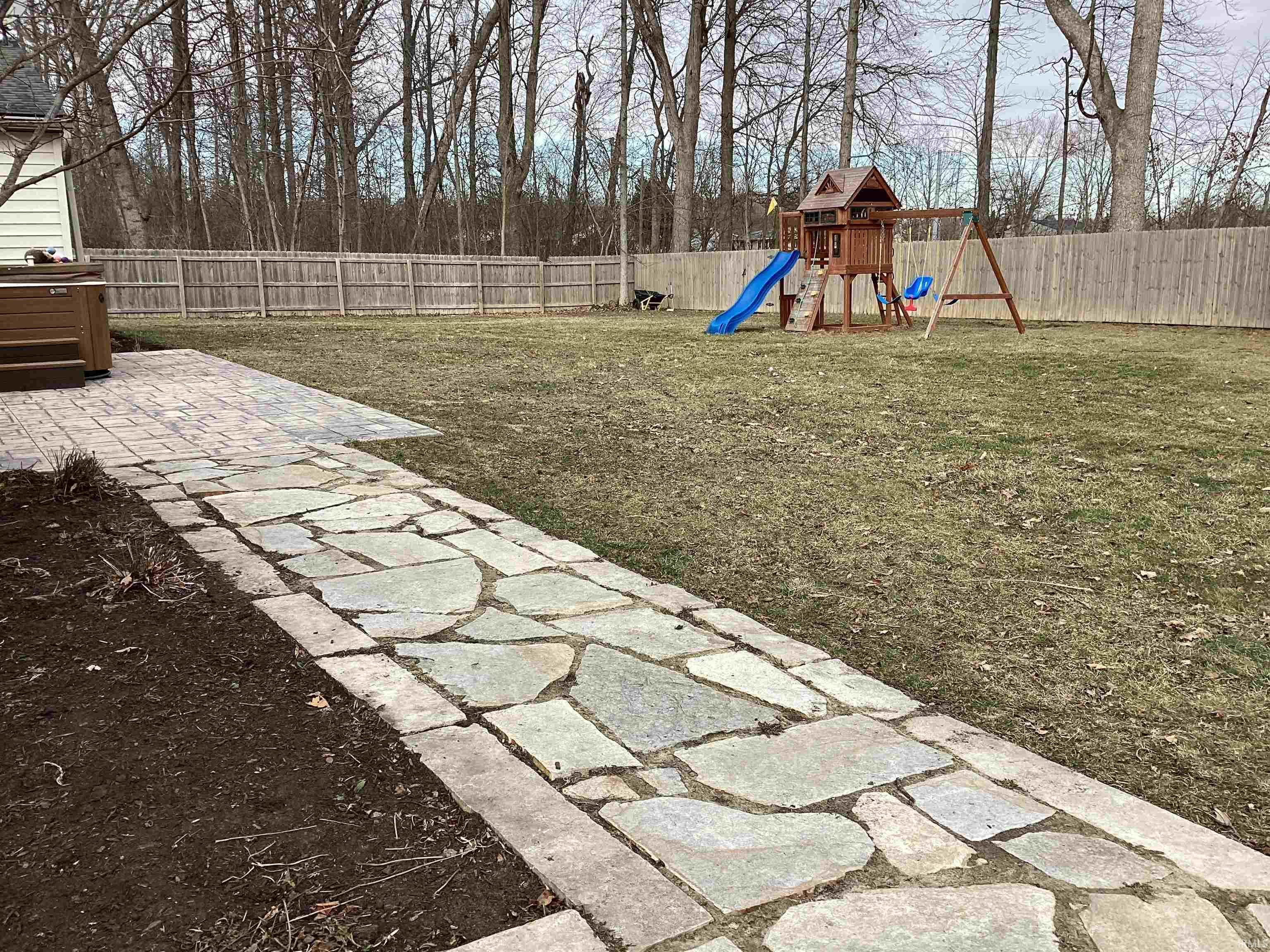 Fenced backyard featuring a playground and a patio area