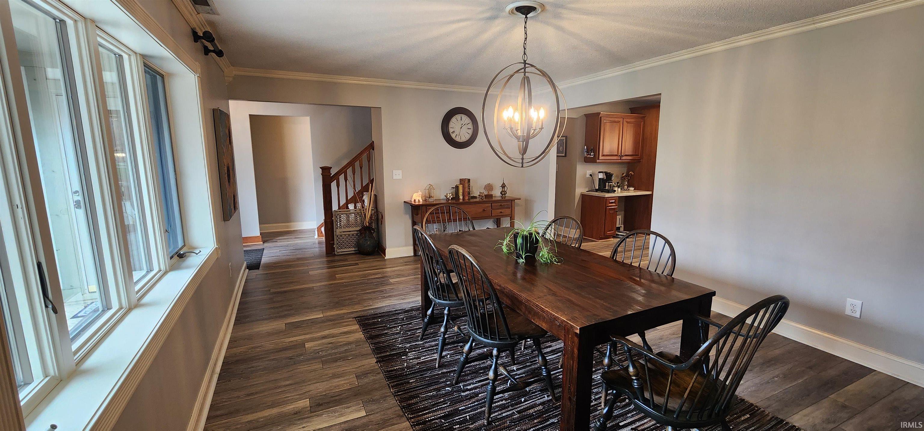 Dining space featuring crown molding, dark wood-style flooring, and a chandelier