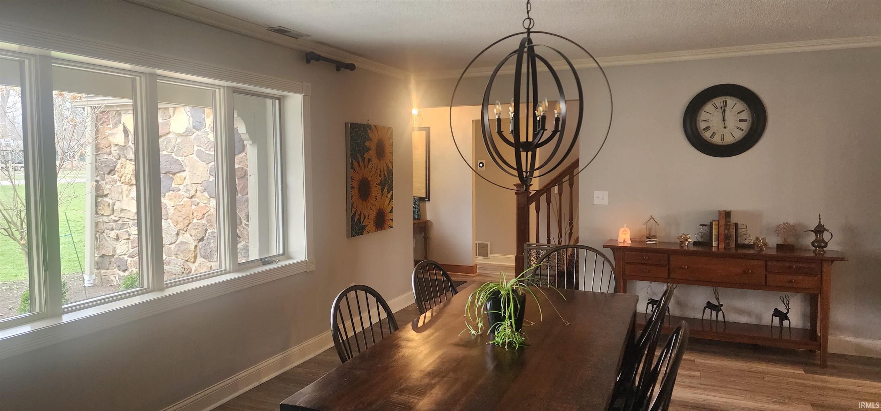 Dining space with crown molding, a chandelier, and wood finished floors