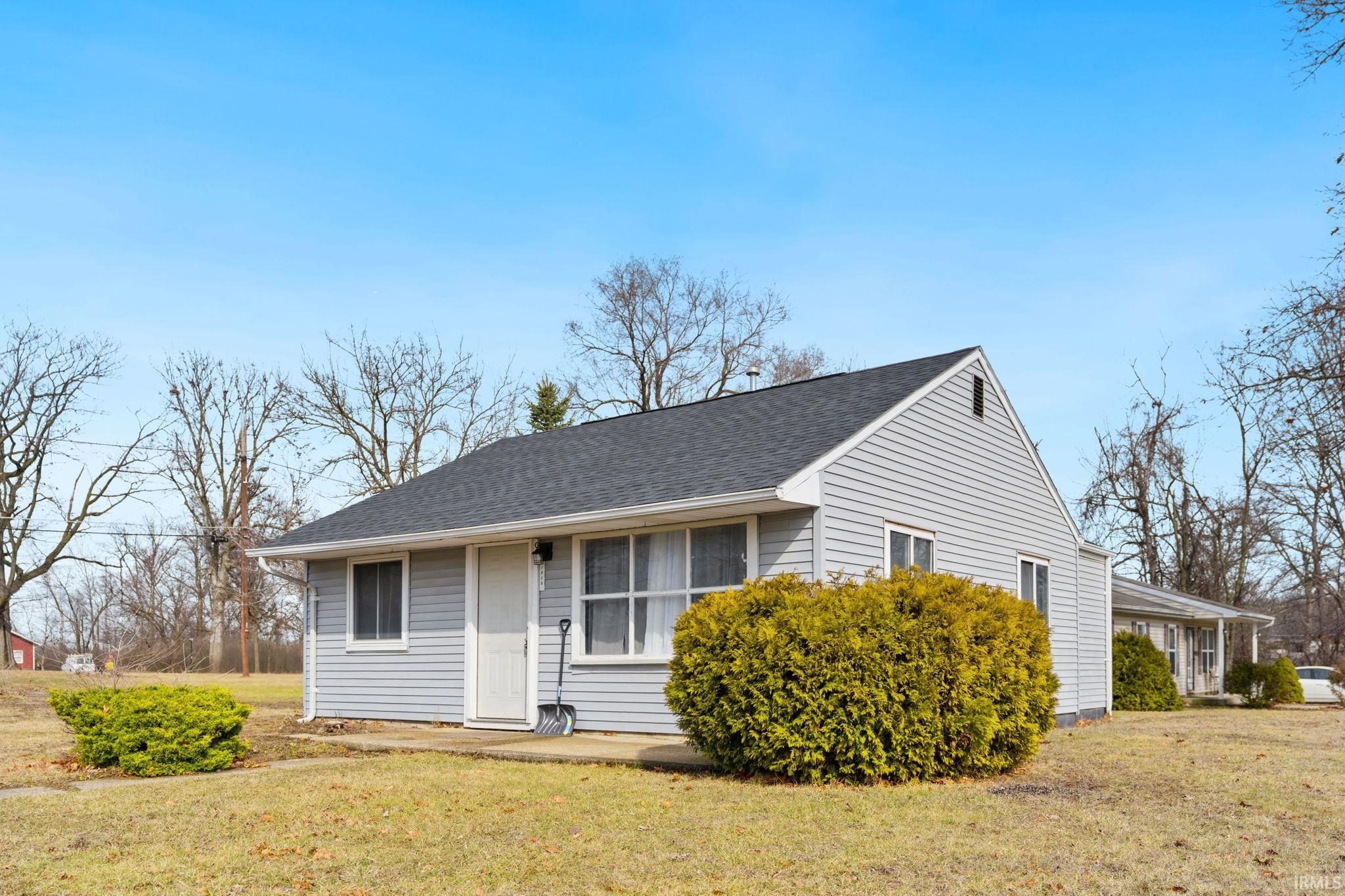 View of front facade with a front yard and a shingled roof