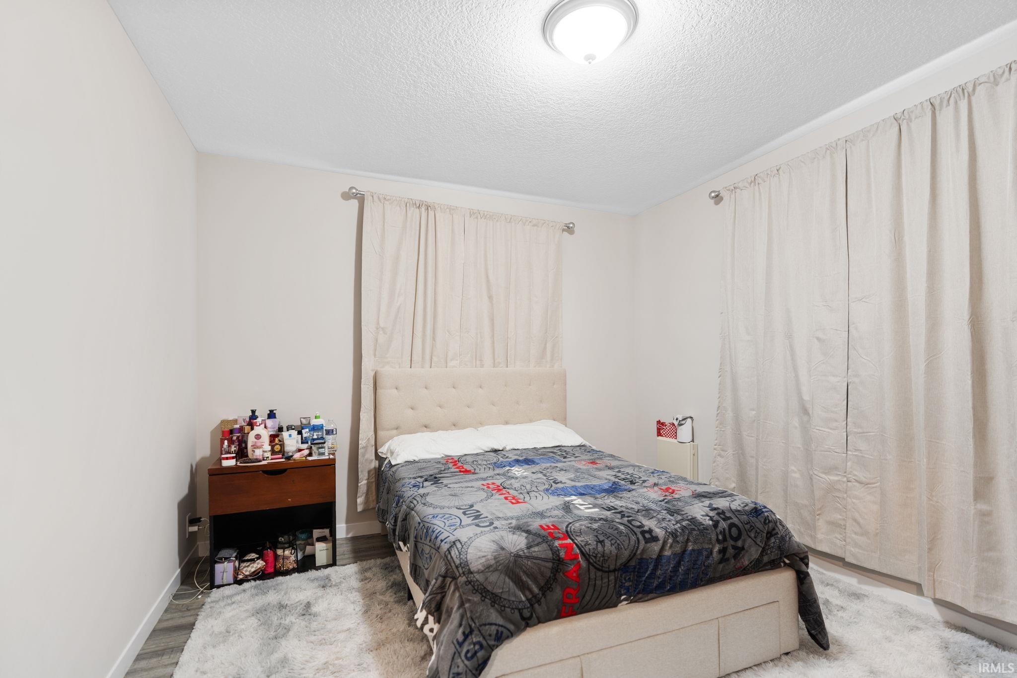Bedroom with light wood-type flooring and a textured ceiling