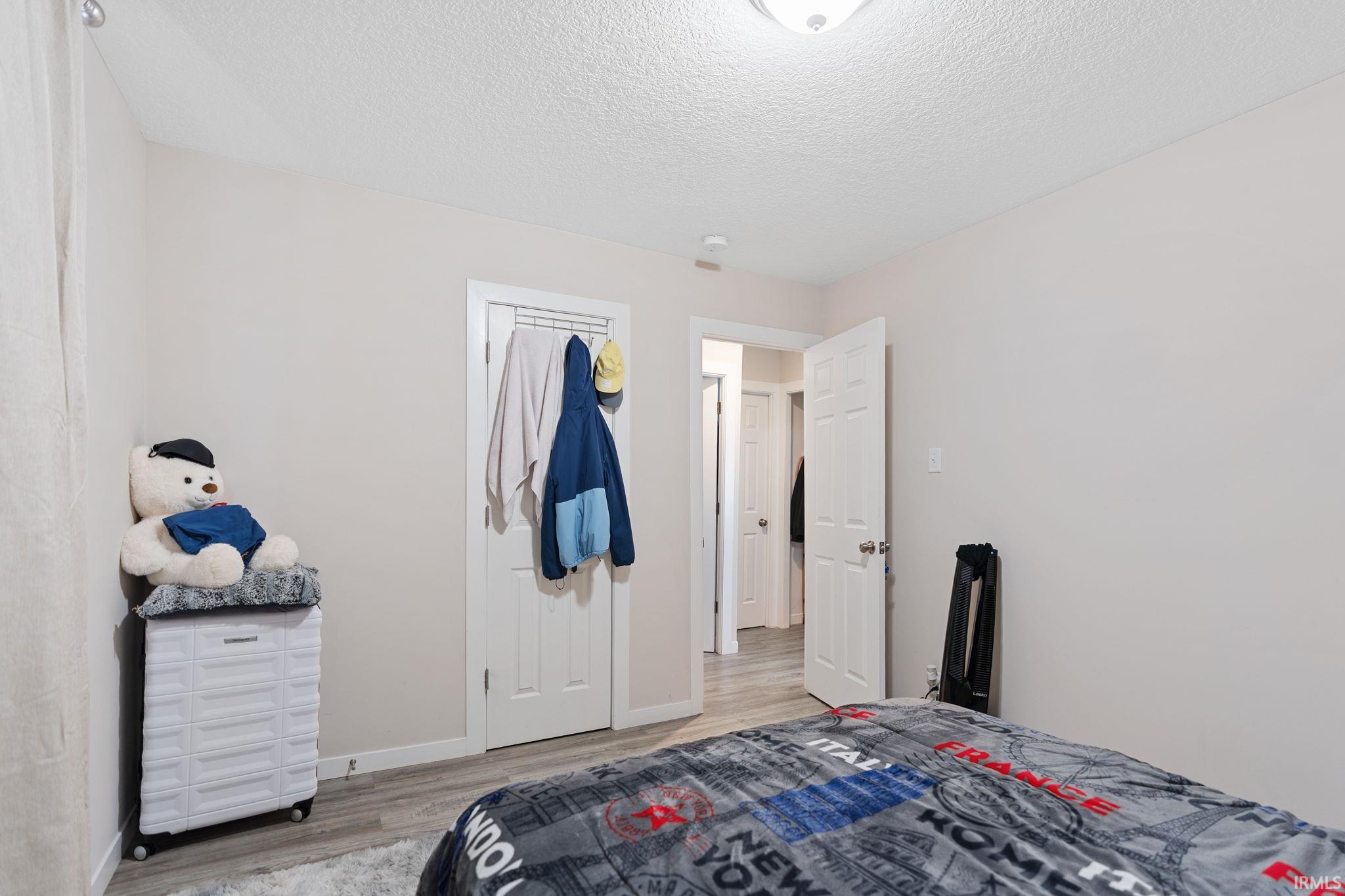 Bedroom with light wood finished floors and a textured ceiling