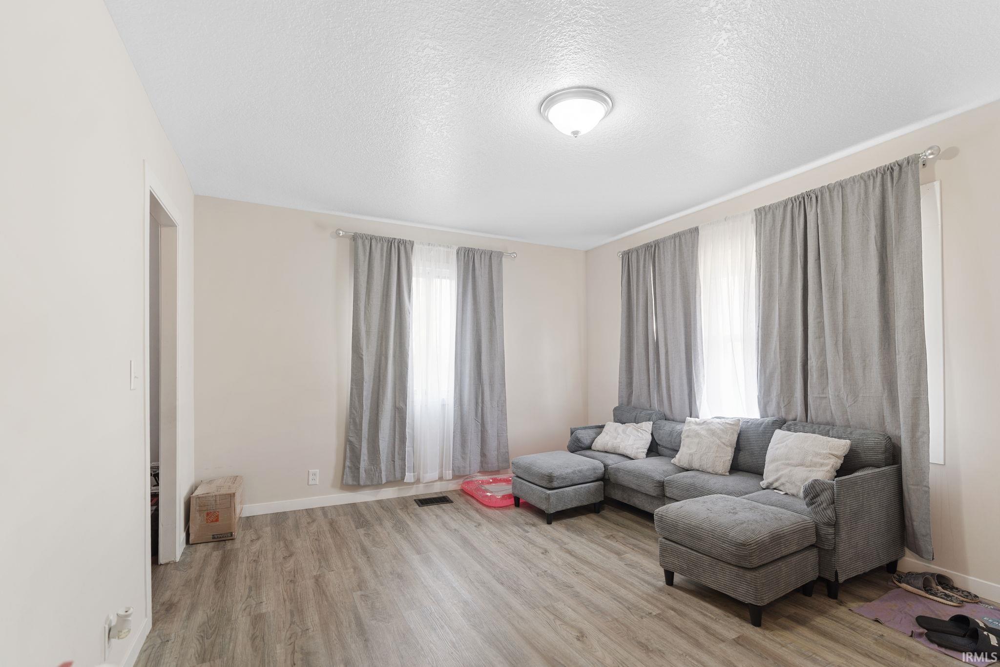 Sitting room with a textured ceiling and light wood-style floors