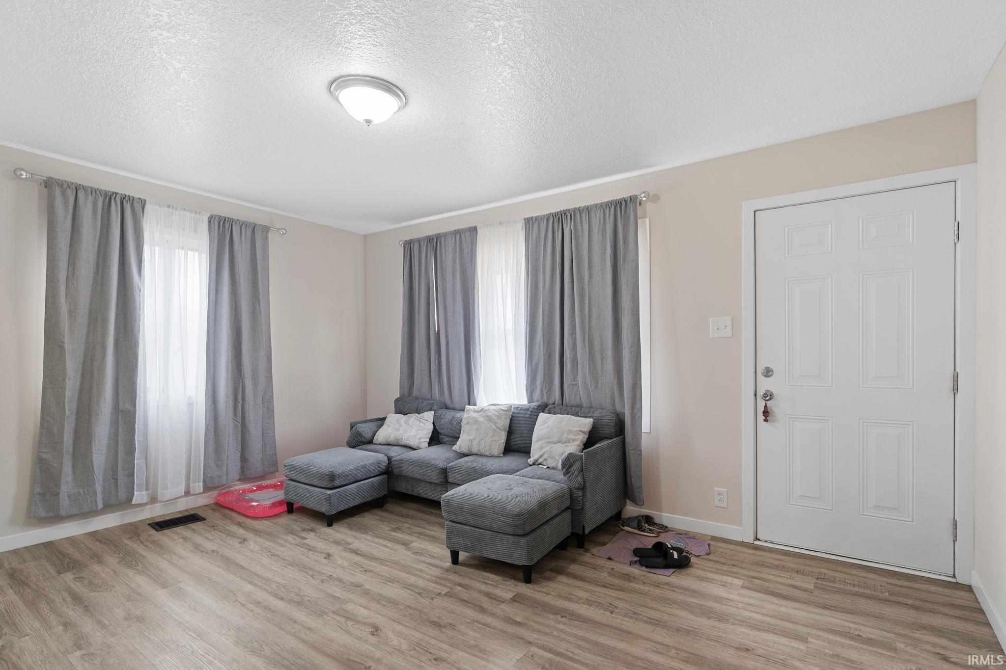 Living room featuring a textured ceiling and light wood-style floors