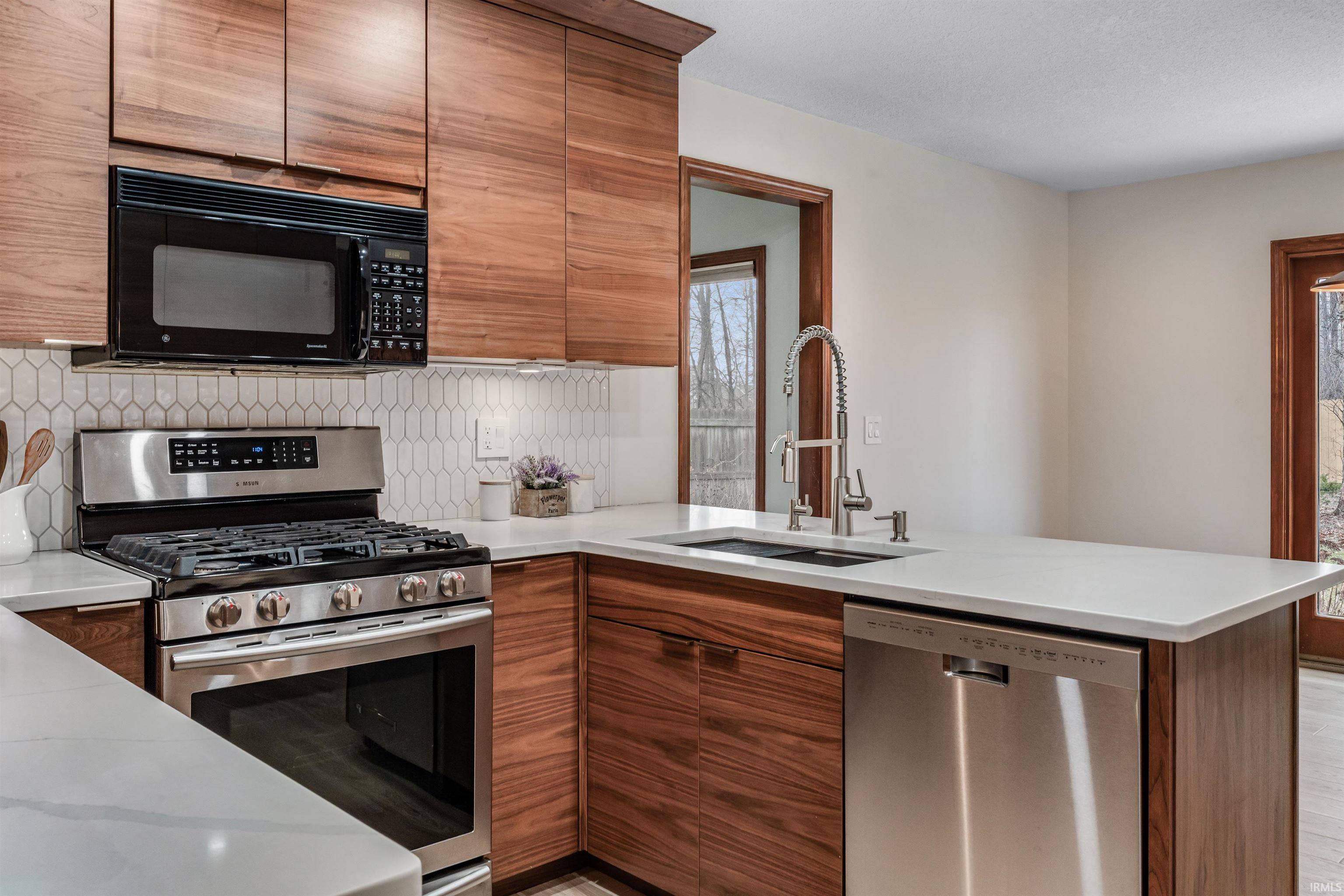 Kitchen featuring stainless steel appliances, a peninsula, wood finish cabinets, and decorative backsplash