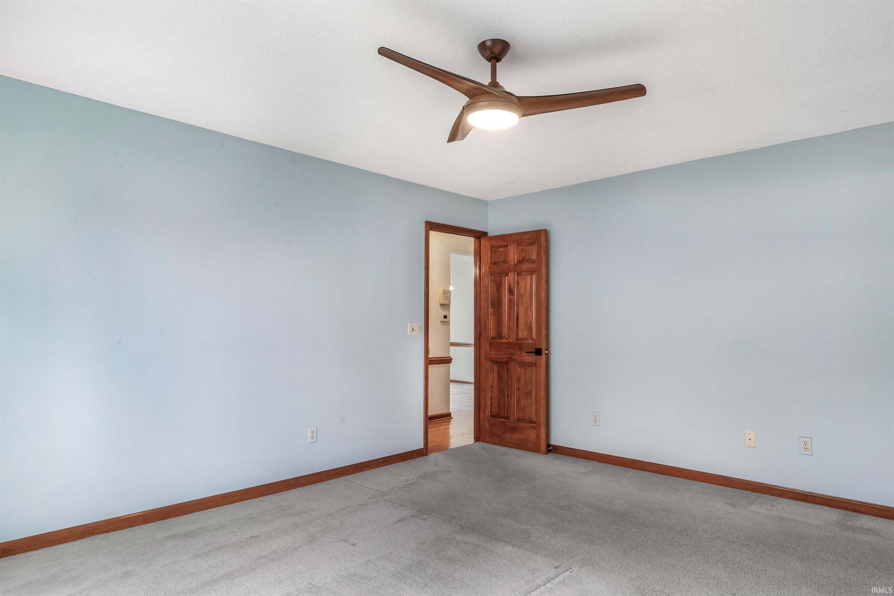 Carpeted empty room with baseboards and a ceiling fan