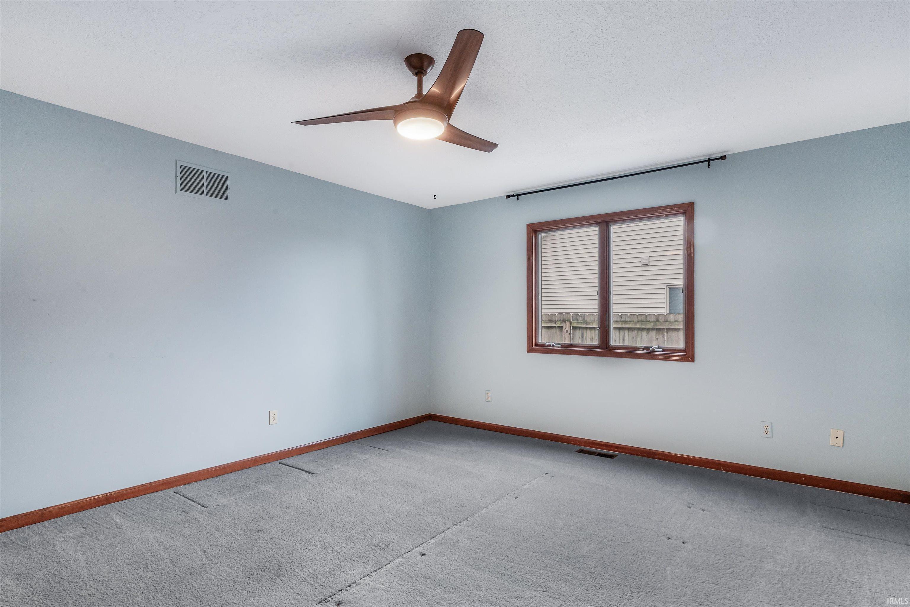 Carpeted spare room featuring baseboards and ceiling fan
