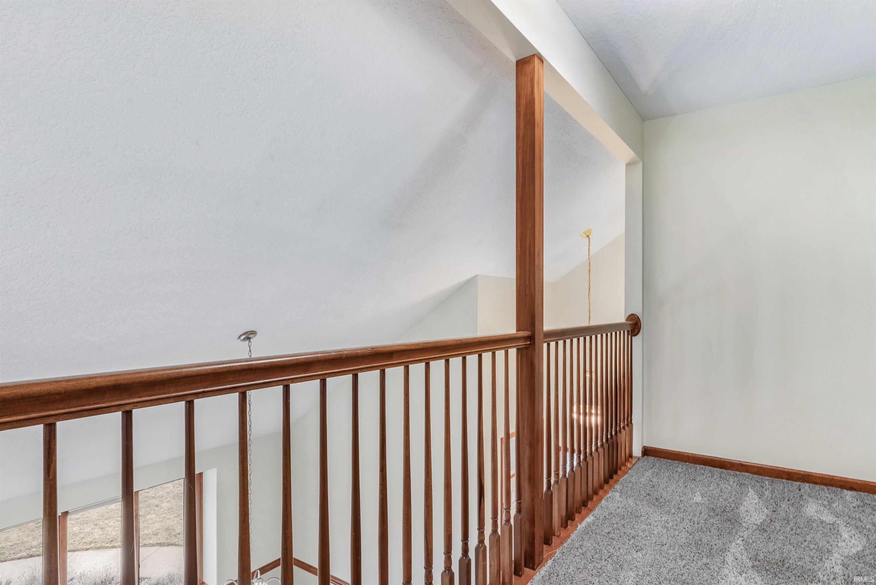 Hallway featuring carpet flooring and lofted ceiling