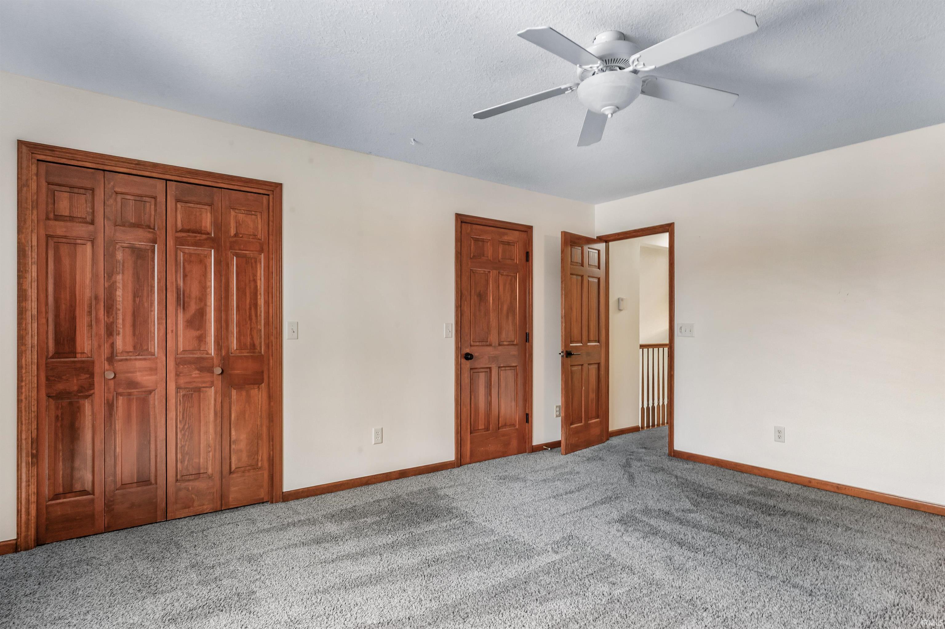 Unfurnished bedroom with carpet, a ceiling fan, and multiple closets