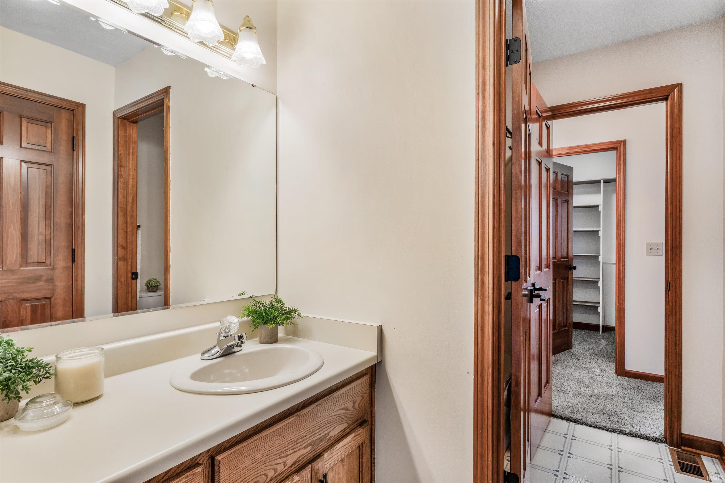 Bathroom featuring vanity, a walk in closet, and light floors
