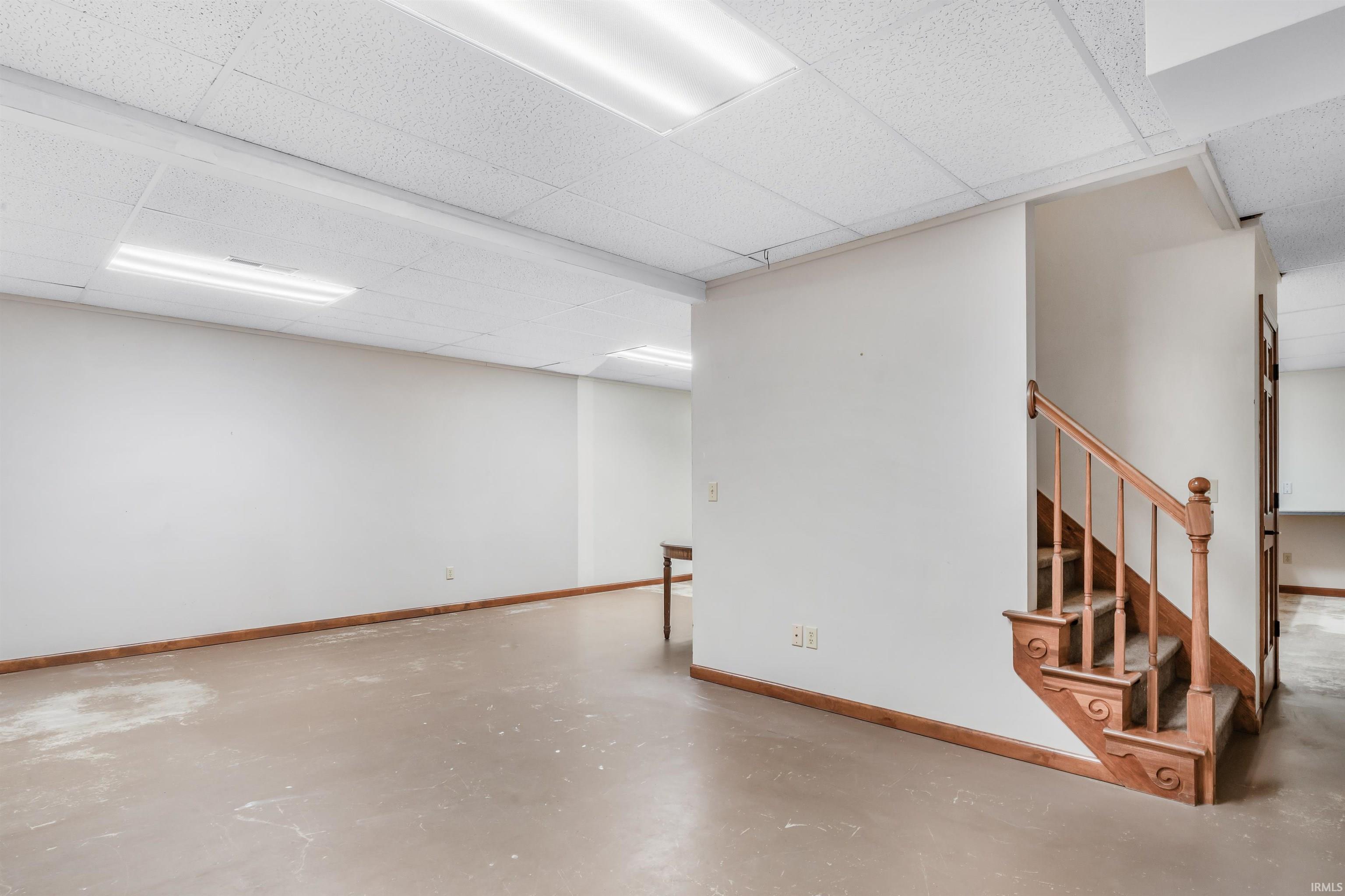 Finished basement with baseboards and a drop ceiling