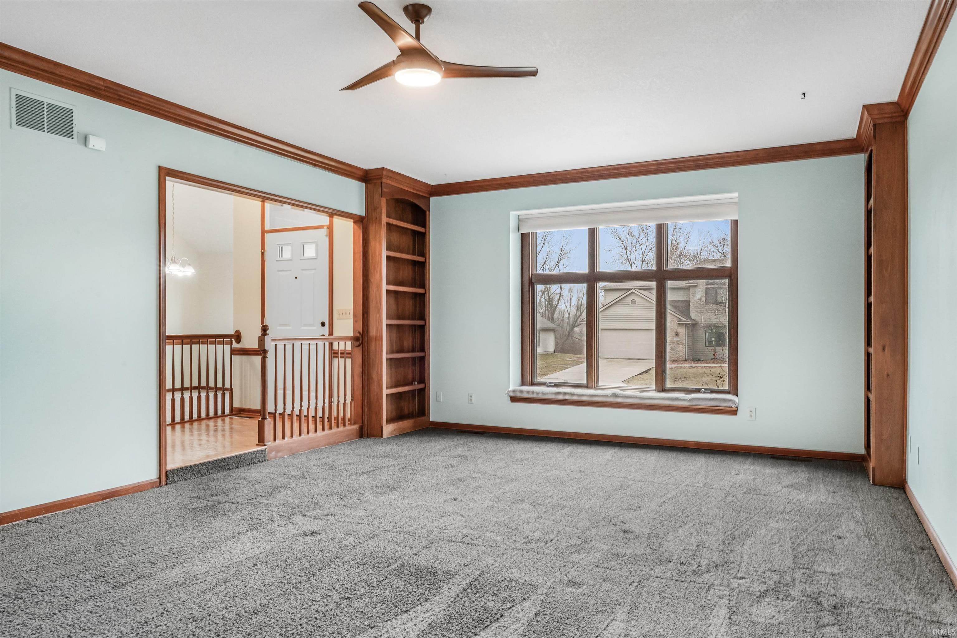 Unfurnished room featuring a ceiling fan, crown molding, and light carpet