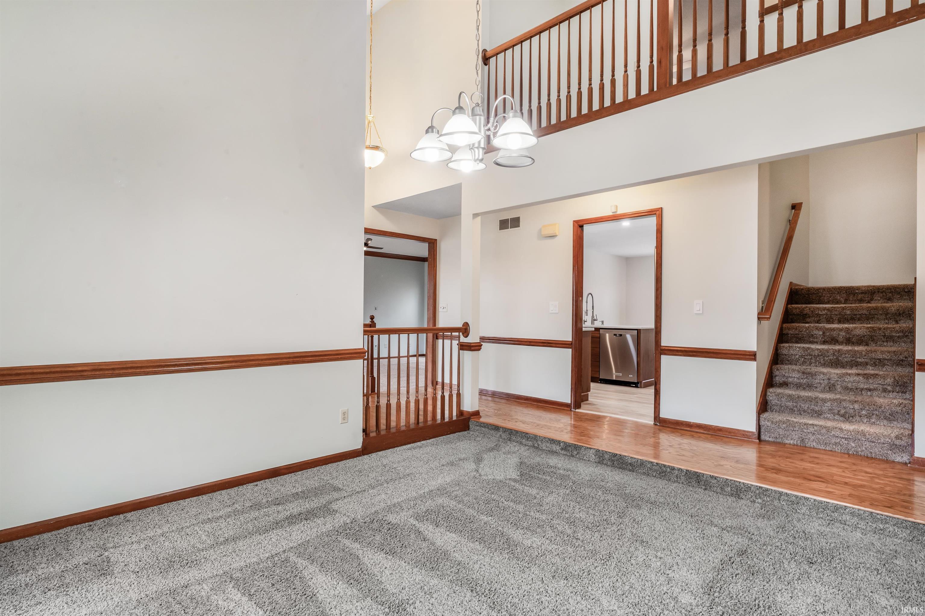 Carpeted spare room featuring a chandelier and a high ceiling