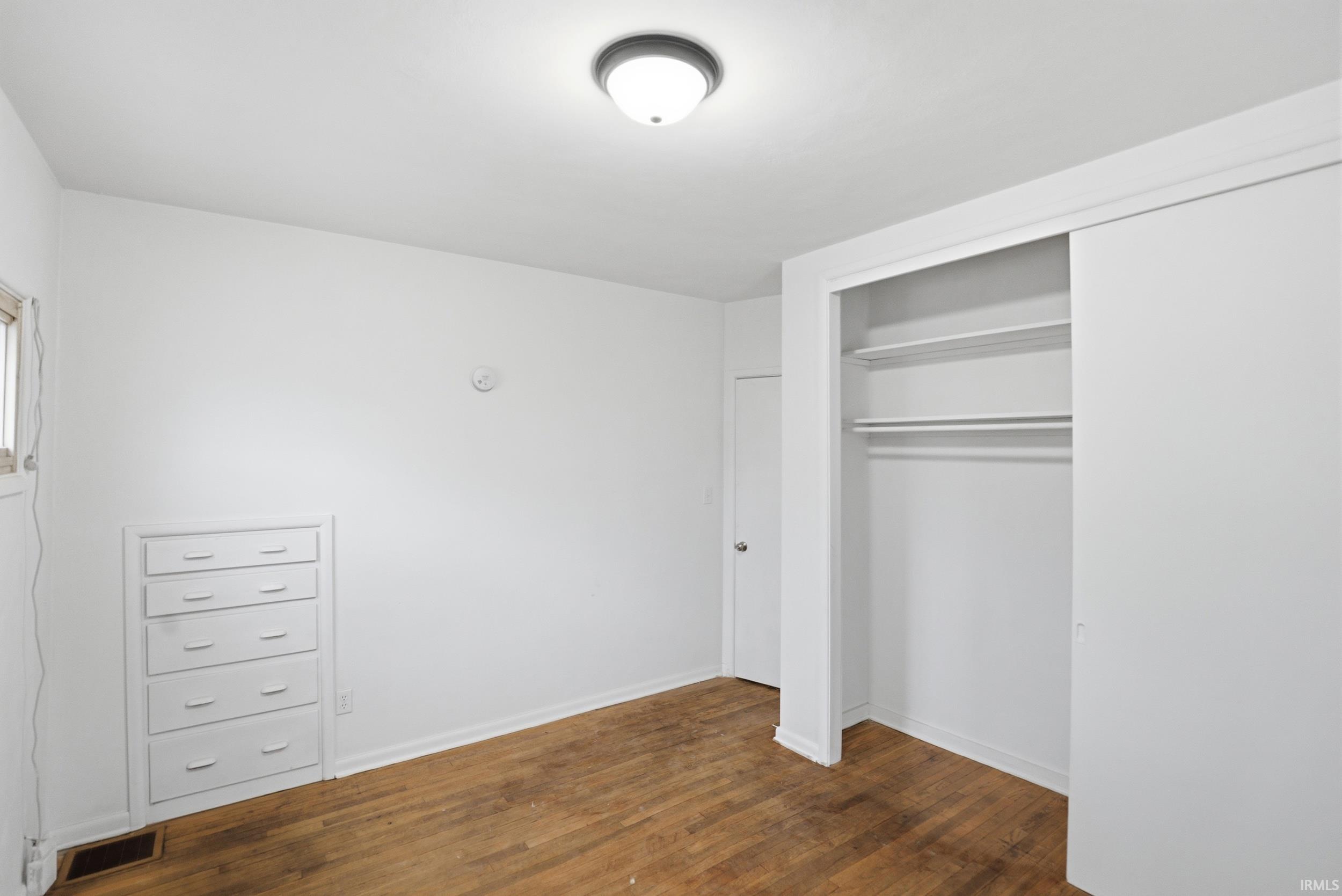 Unfurnished bedroom featuring dark wood finished floors and a closet