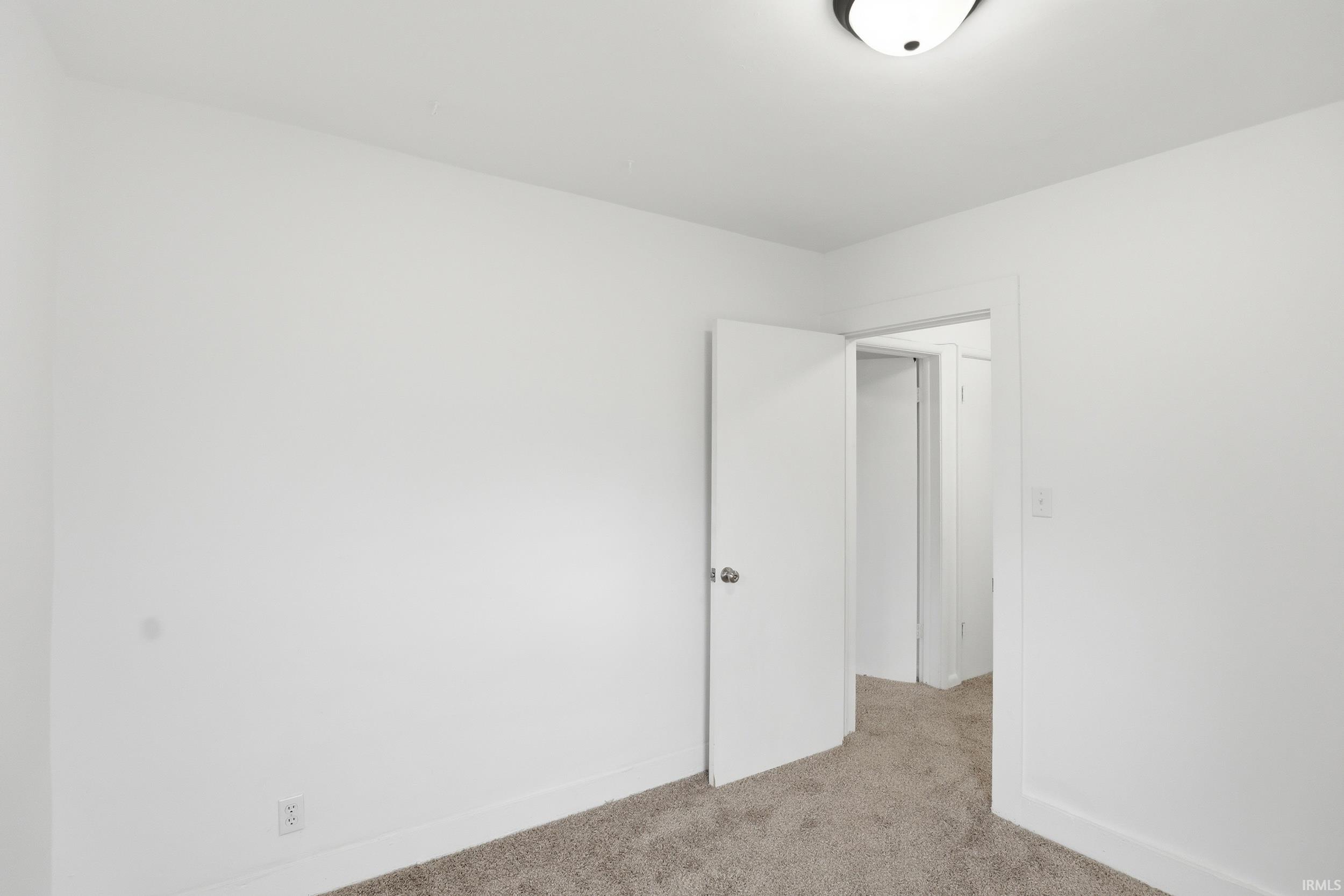 Unfurnished room with light colored carpet and baseboards
