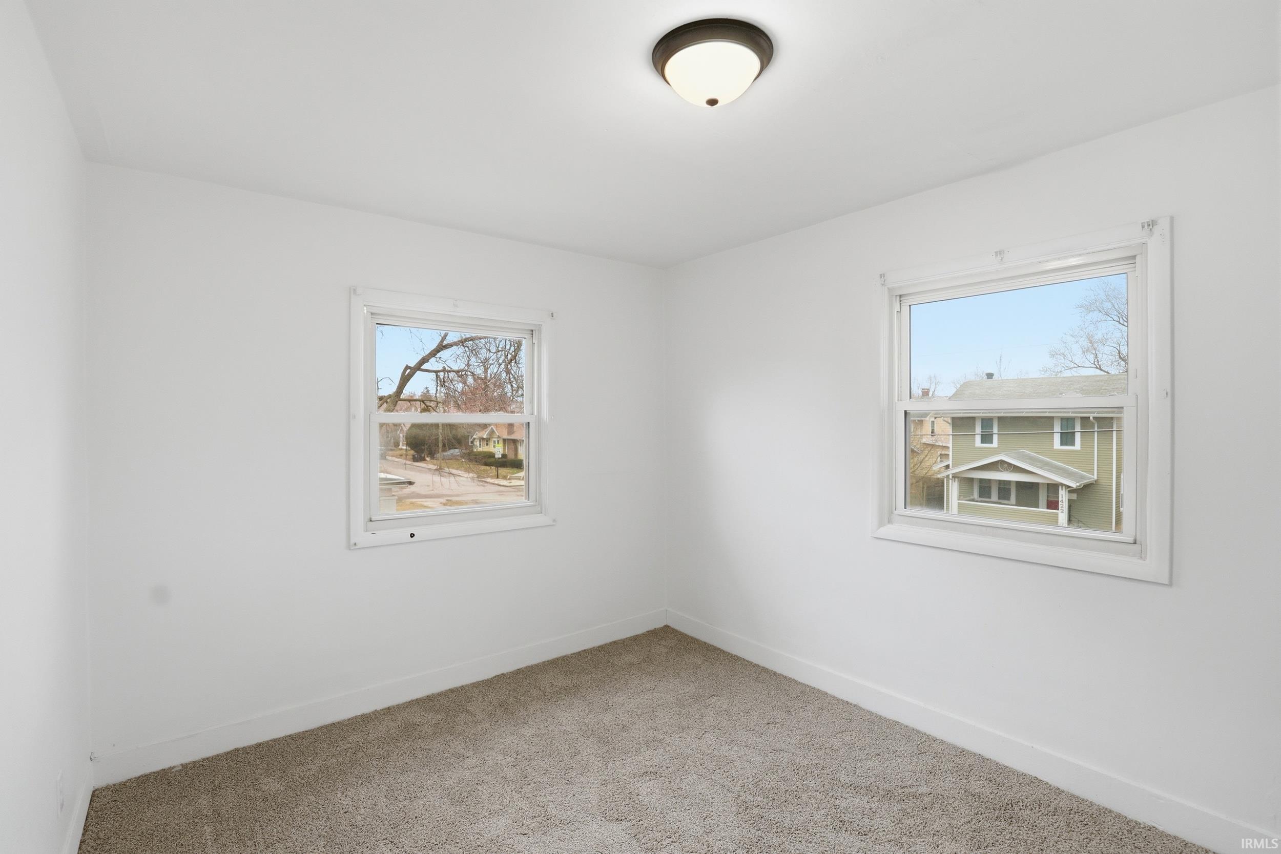 Spare room with baseboards and light colored carpet