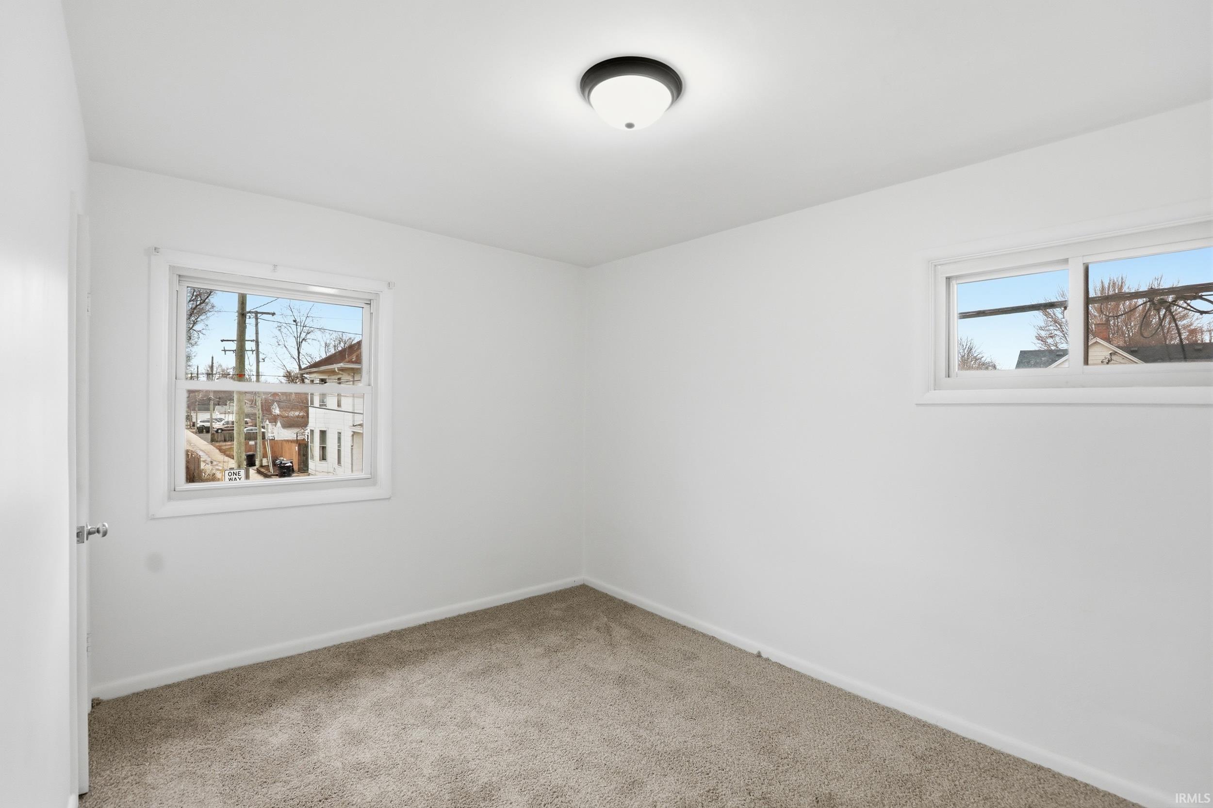 Empty room with light colored carpet and baseboards