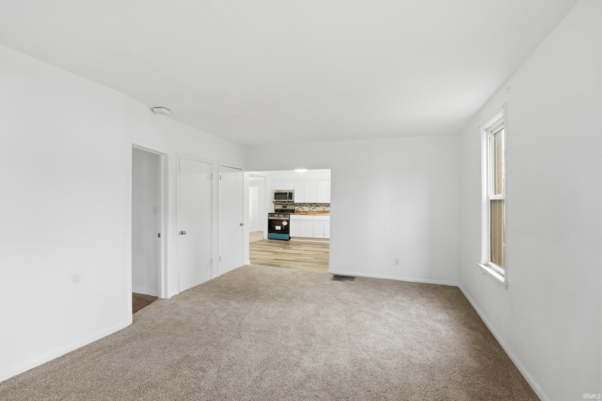 Spare room with light colored carpet and baseboards