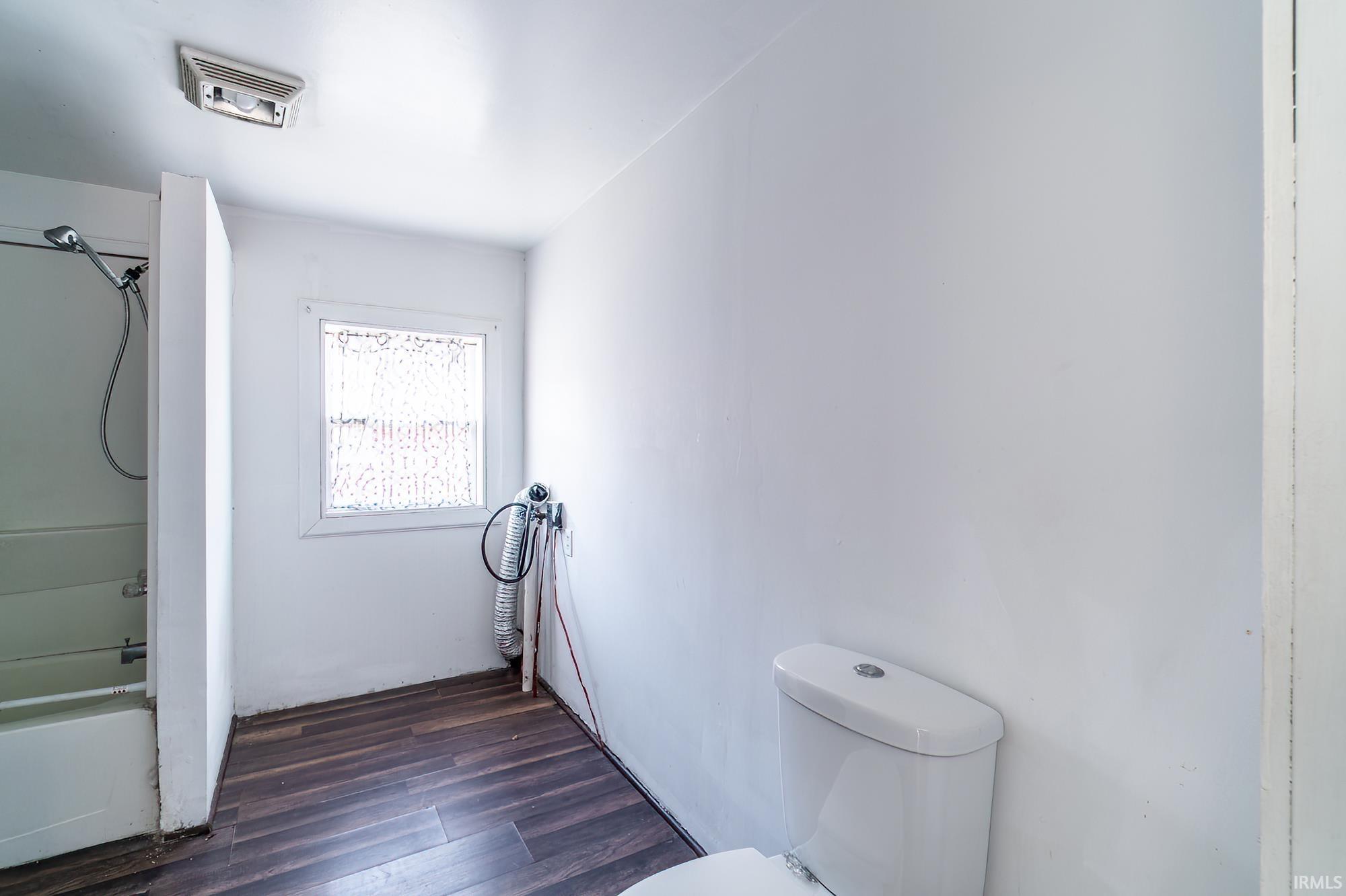 Full bath featuring dark wood-type flooring and washtub / shower combination