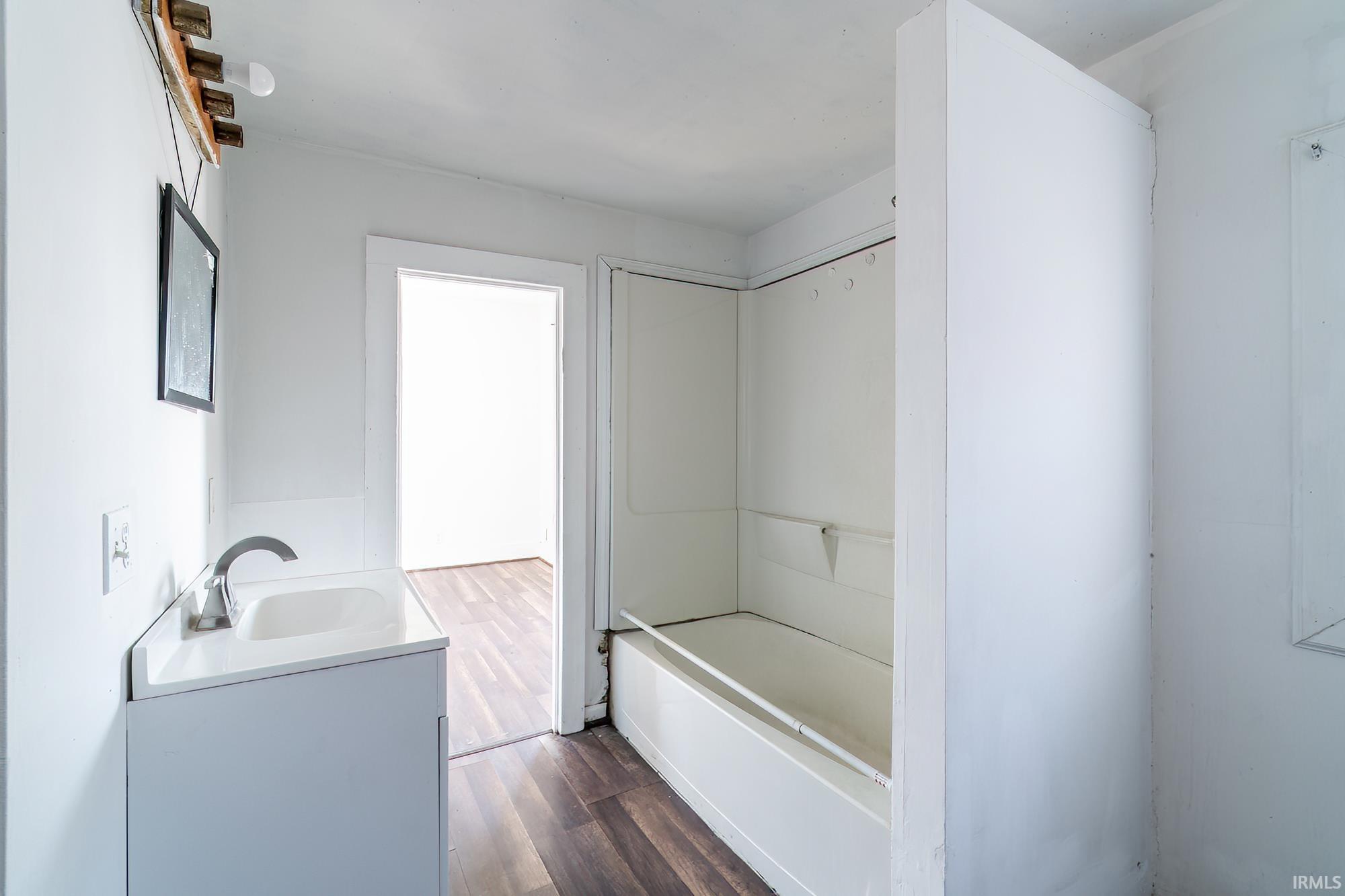 Full bathroom with vanity, dark wood-style flooring, and a bathtub